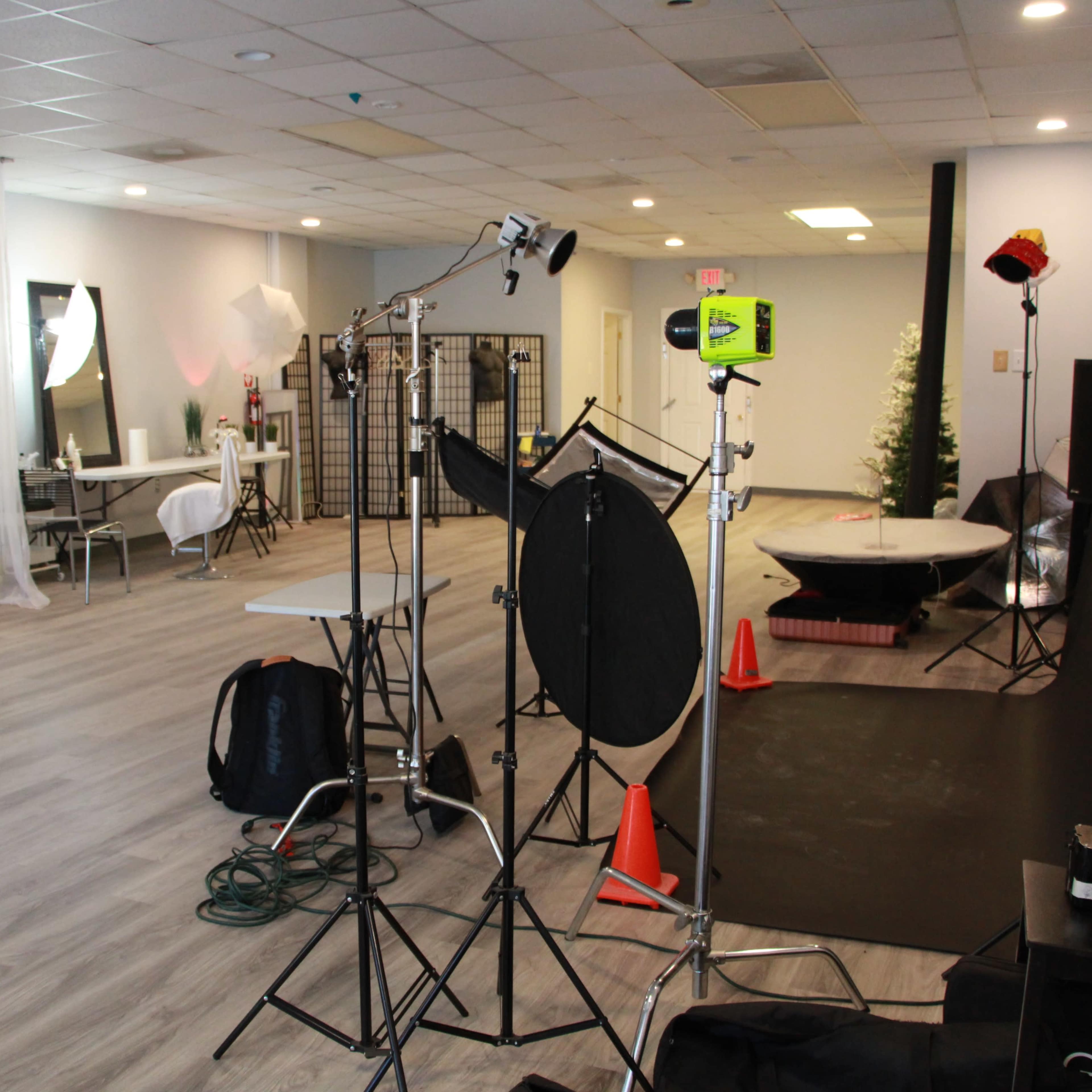 A spacious photo studio with lighting equipment, backdrops, and various props arranged throughout the area.