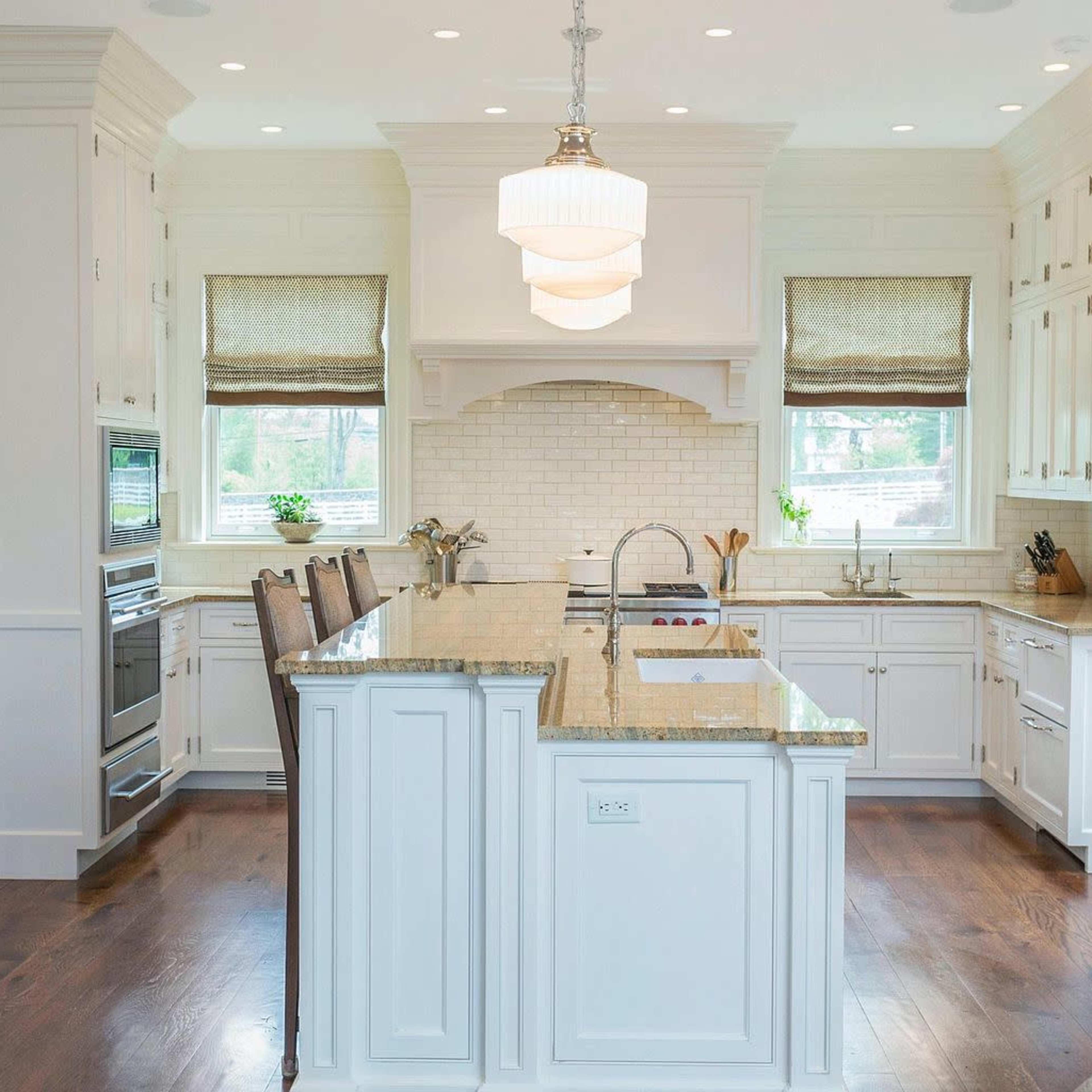 The kitchen features white cabinetry, a central island with a granite countertop, and stainless steel appliances.