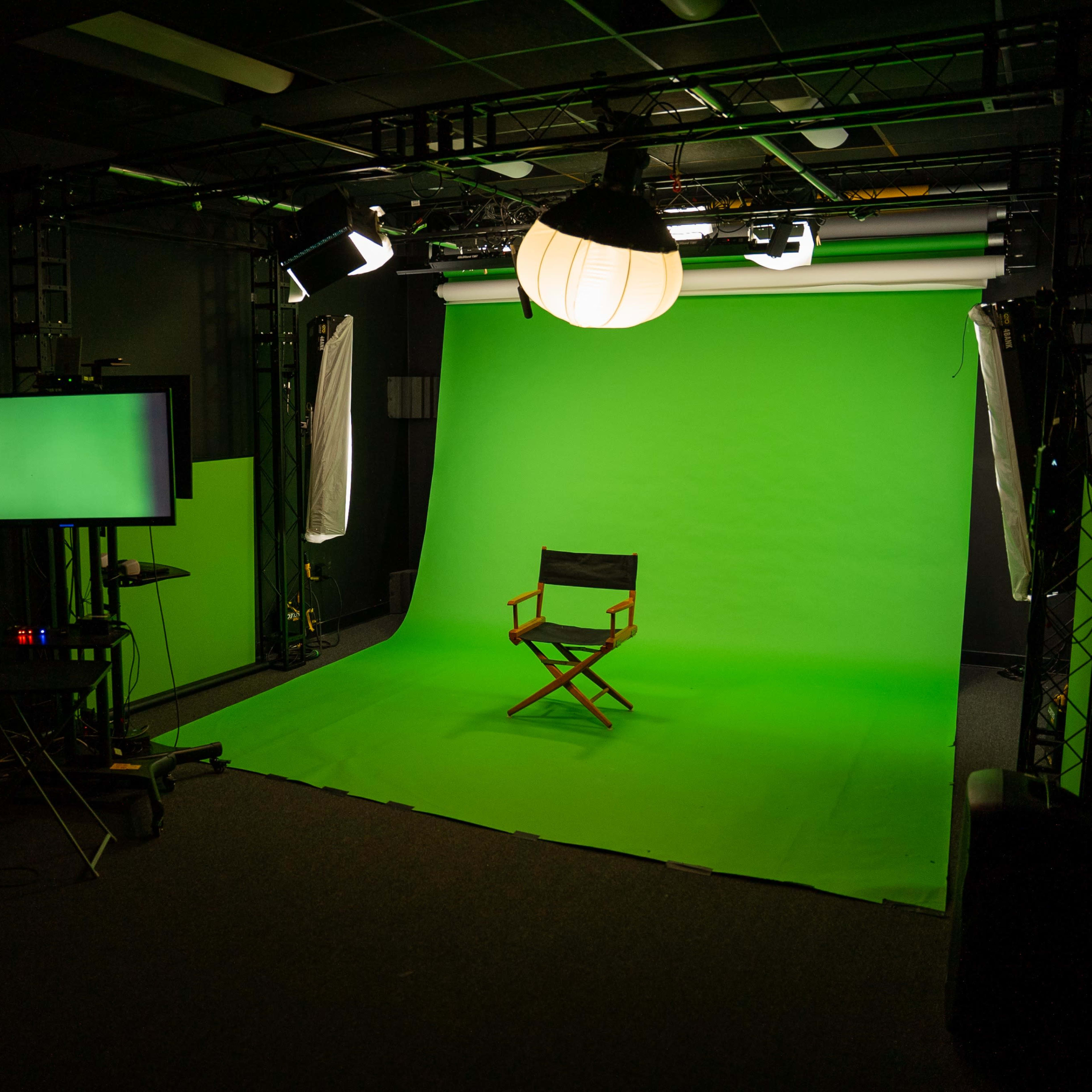 A green screen studio setup with a director's chair positioned in front of an illuminated green backdrop.