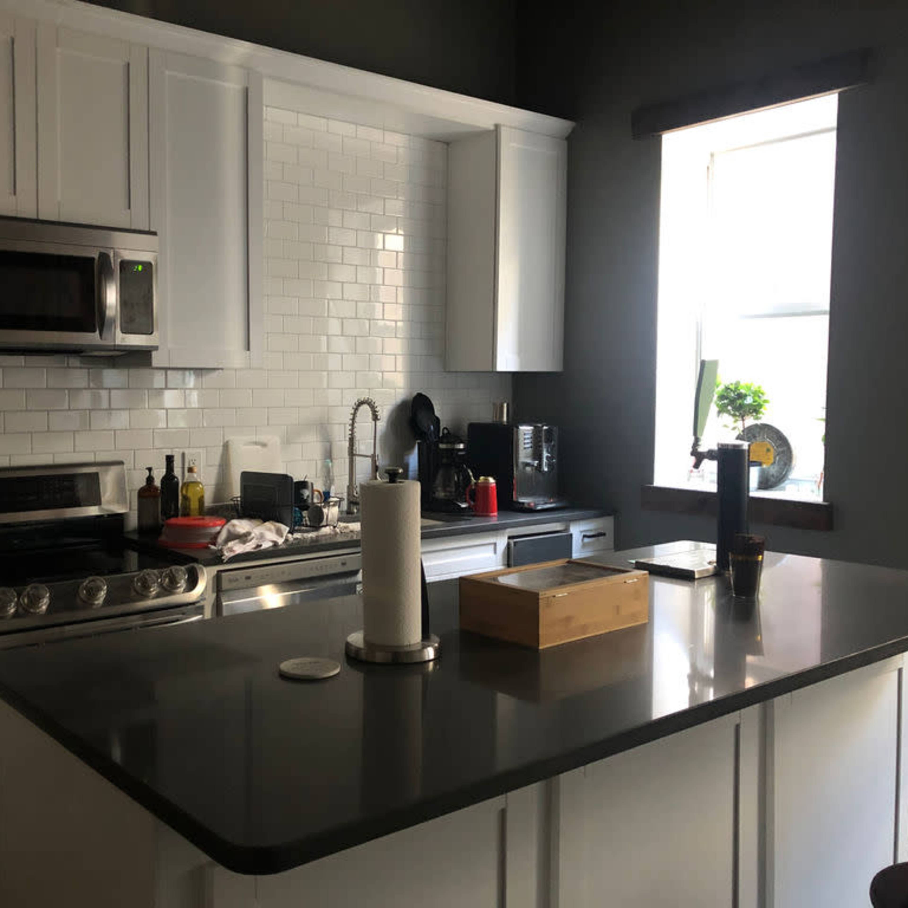 A modern kitchen with white cabinets, stainless steel appliances, and a central island.