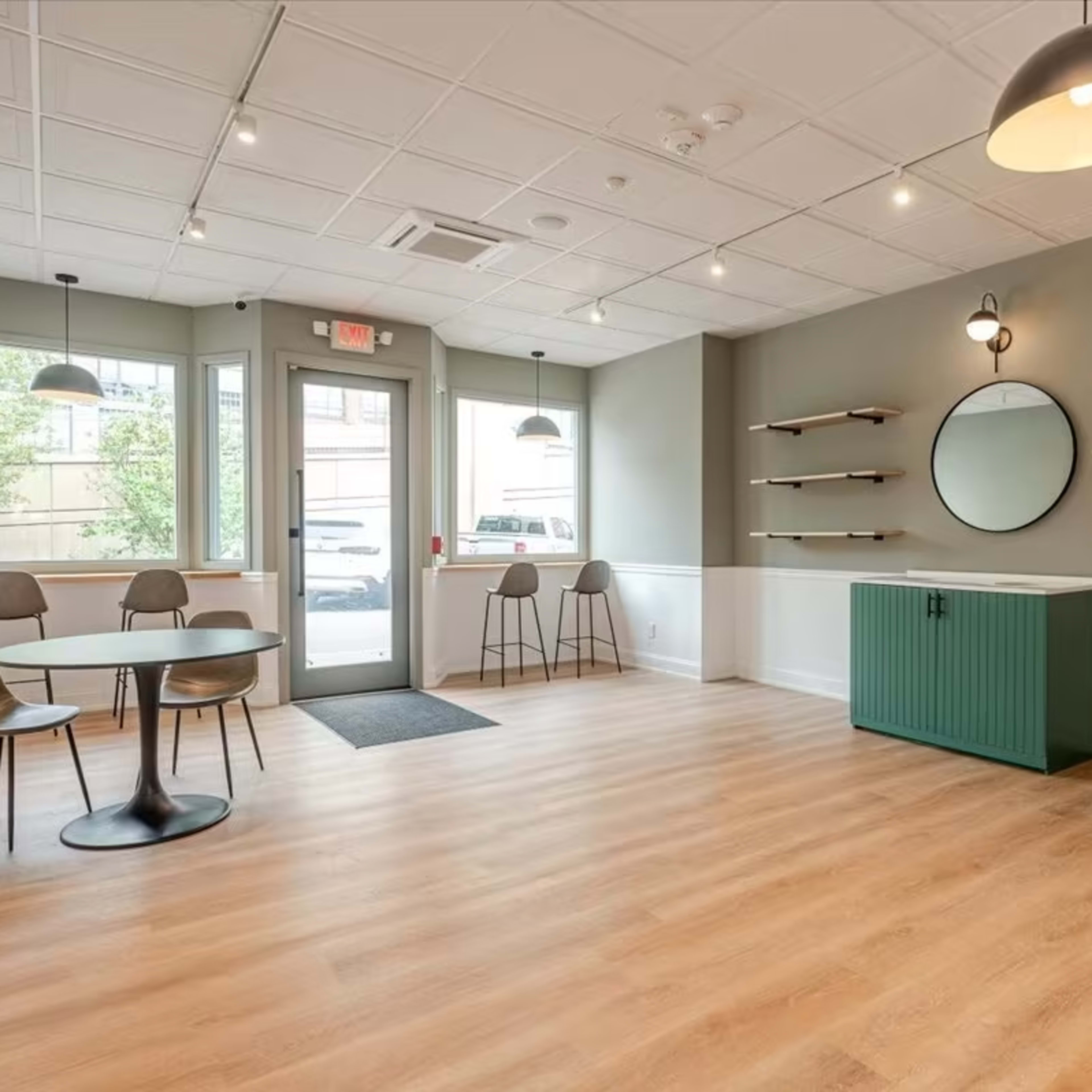 A modern, minimalist interior with a round mirror and shelves on the wall, featuring a table and four chairs in a light-filled room.