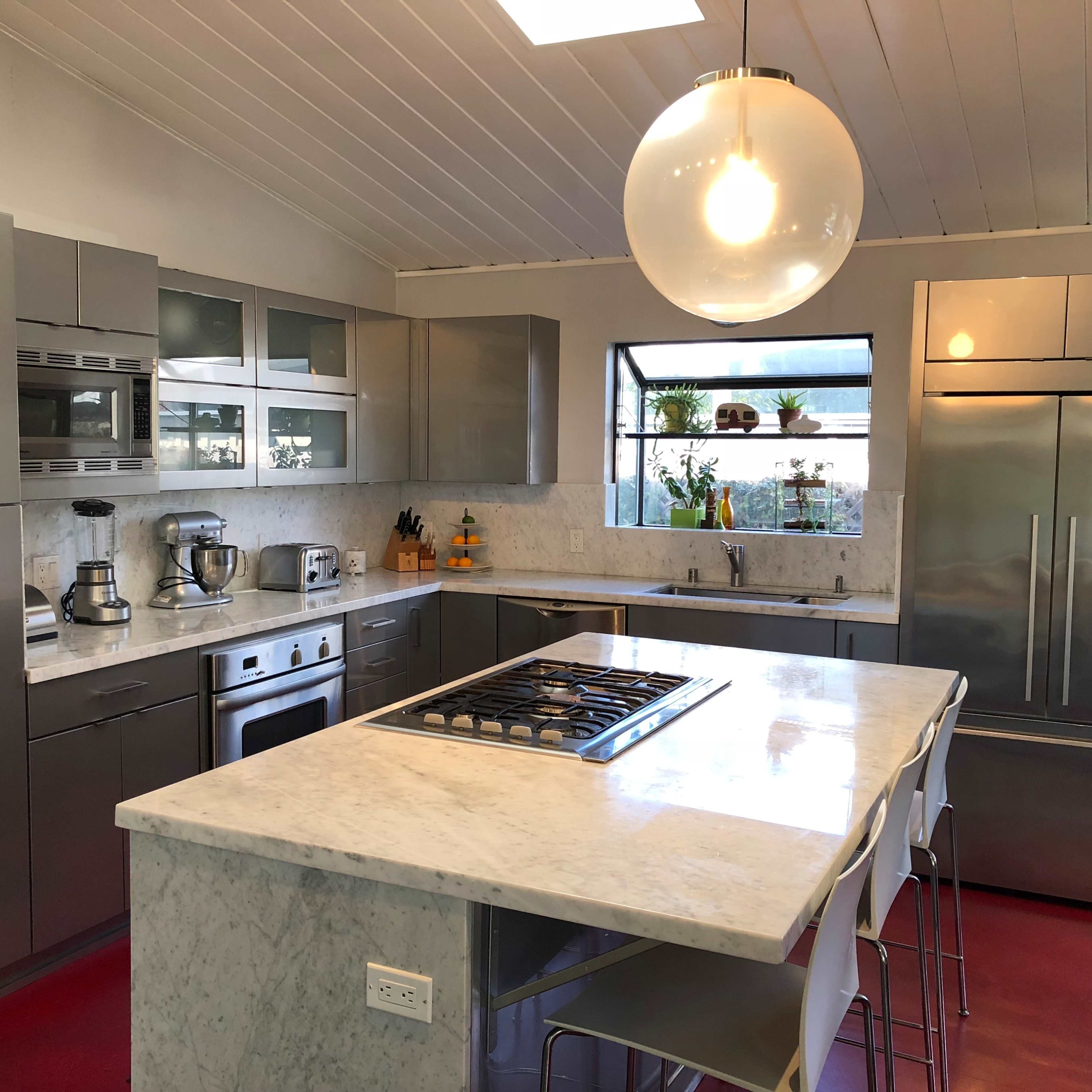 A modern kitchen with stainless steel appliances, marble countertops, and a central island with seating.