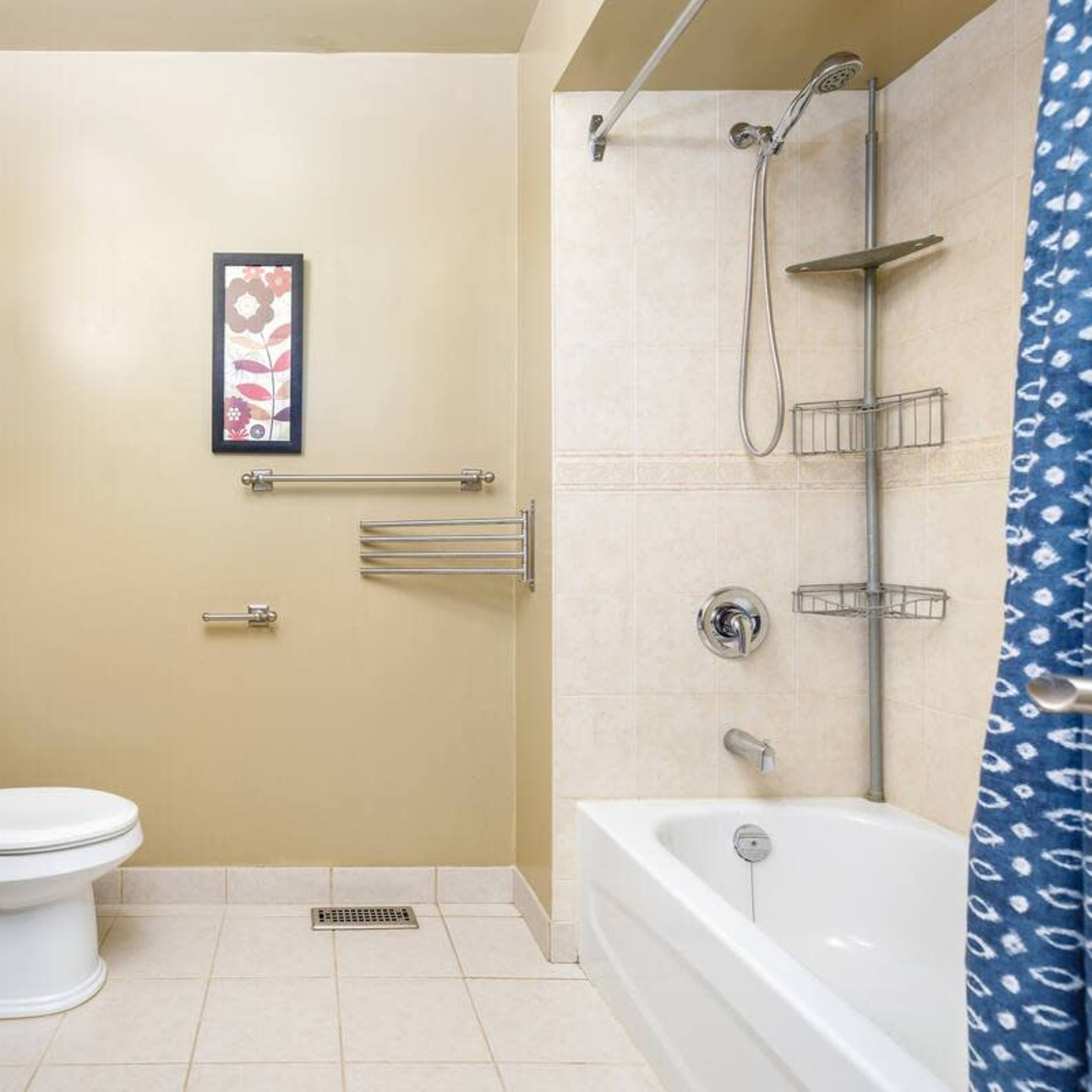 A bathroom featuring a shower and bathtub combination, a toilet, a sink with a dark wood cabinet, and wall-mounted storage.