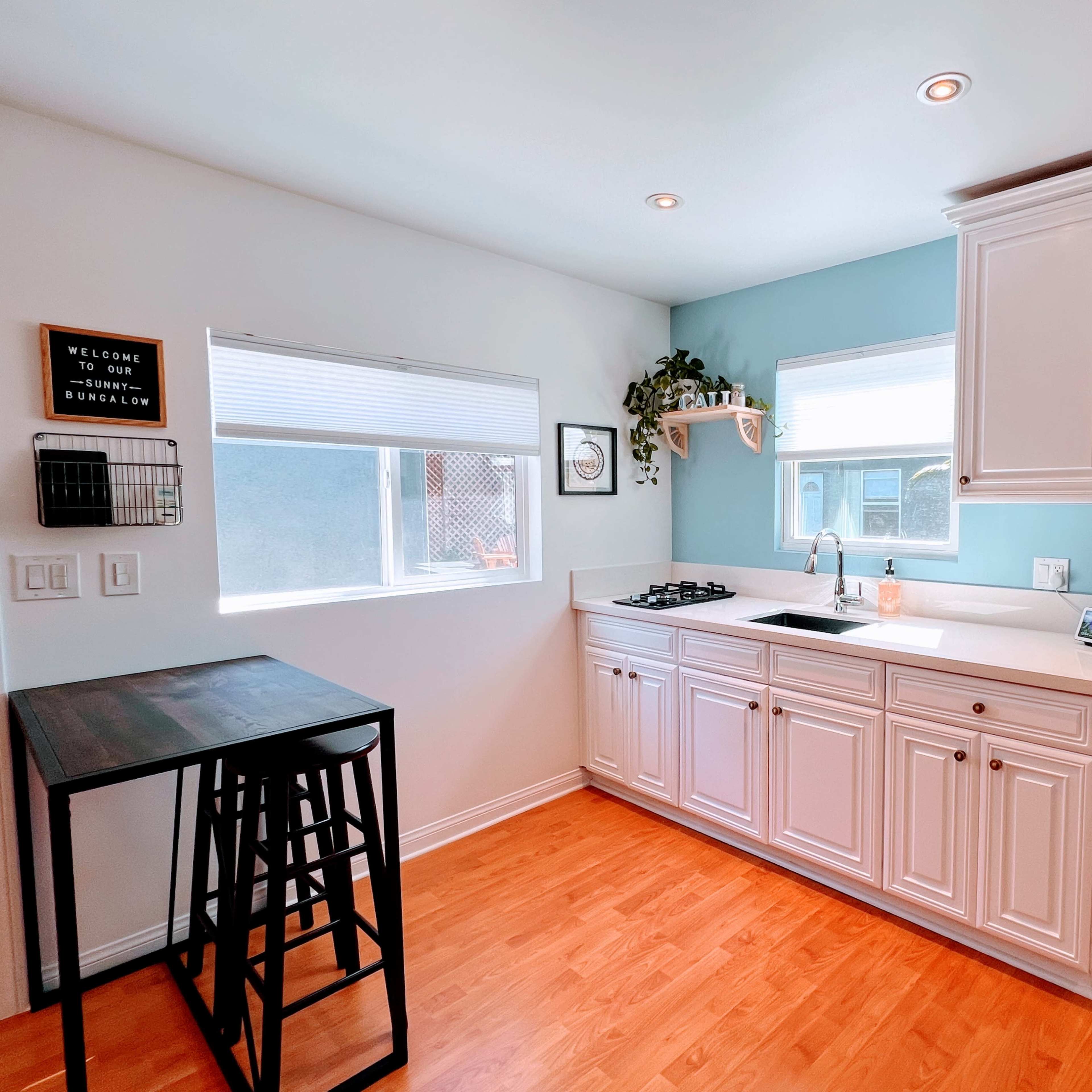A modern kitchen with white cabinetry, a stainless steel refrigerator, and a window providing natural light.