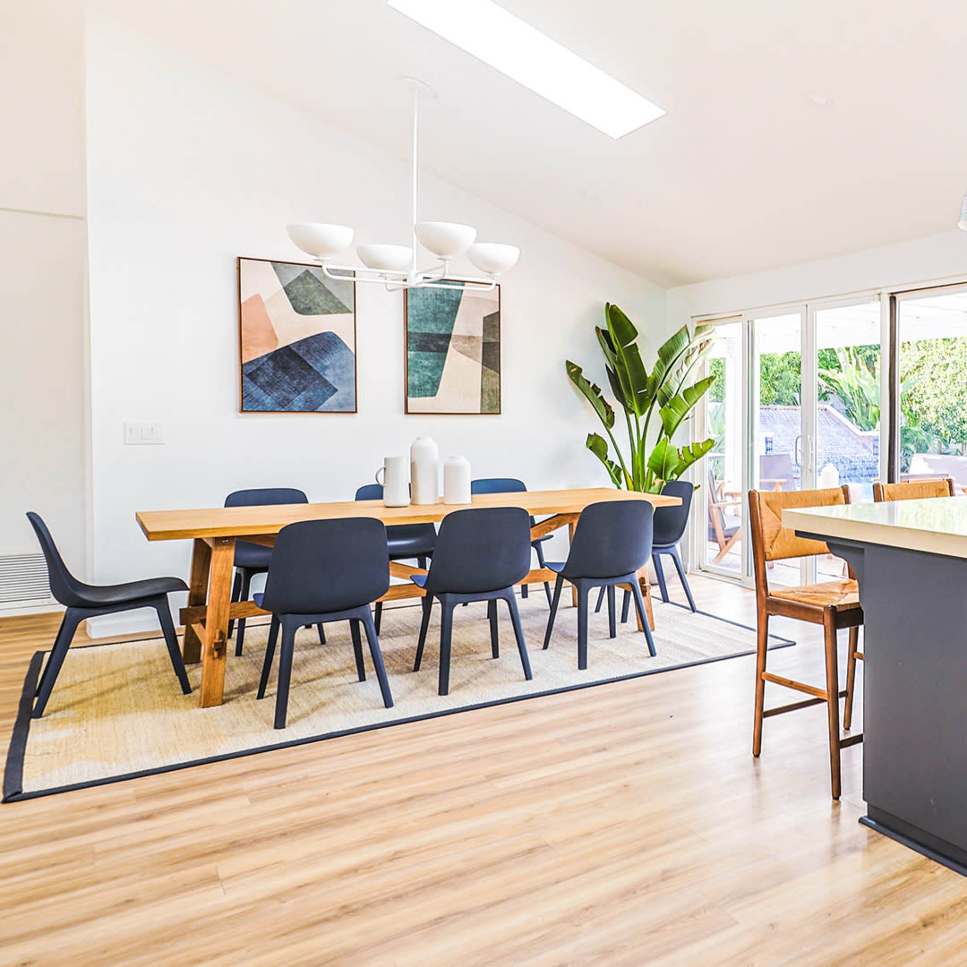 A bright, modern kitchen connected to a dining area with a large table and sliding glass doors leading to an outdoor space.