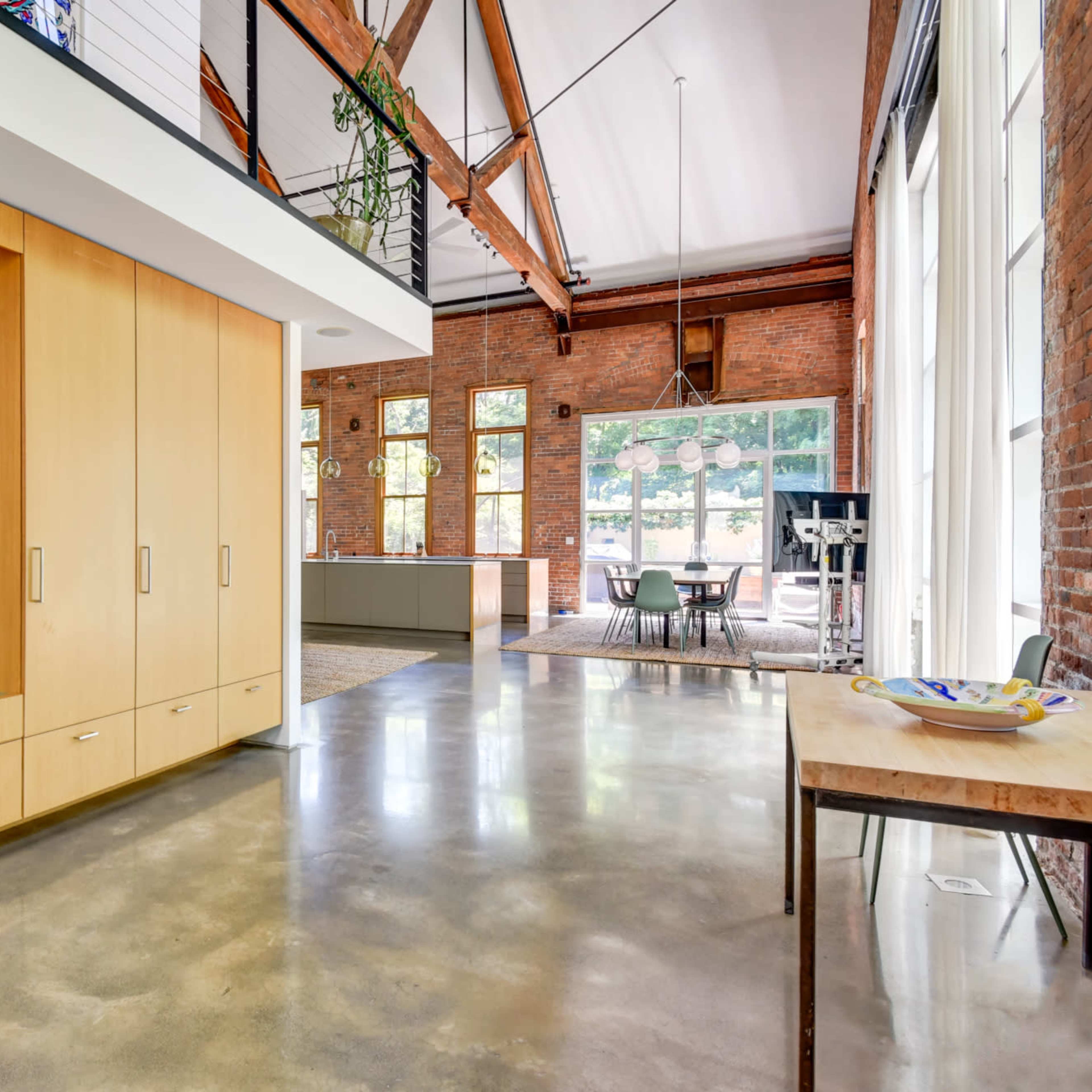A modern interior space featuring a wooden cabinetry unit, large windows, and an open layout connecting to a dining area.