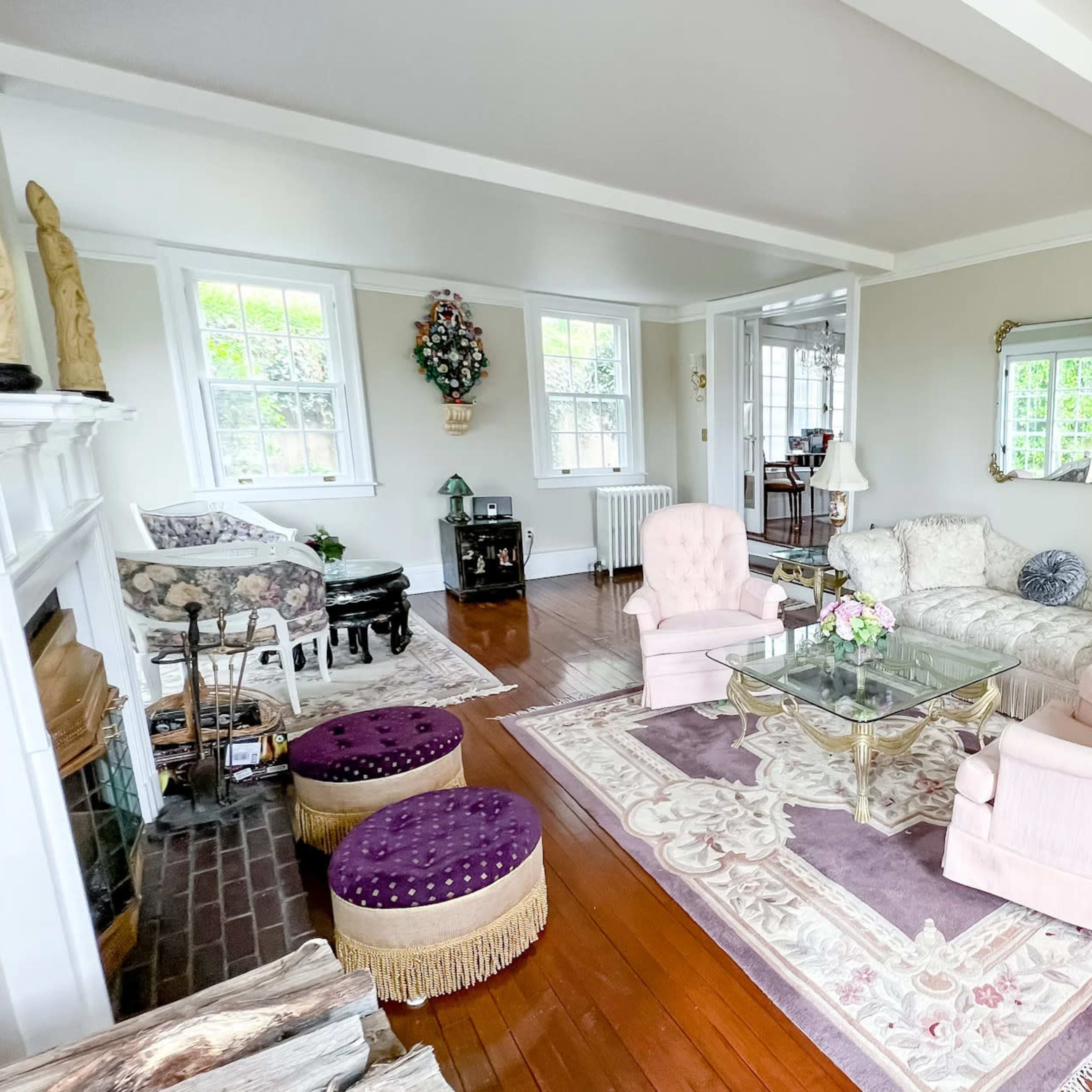 The living room features a light-colored sofa, two armchairs, a coffee table, and decorative accents, all set on polished wooden flooring.
