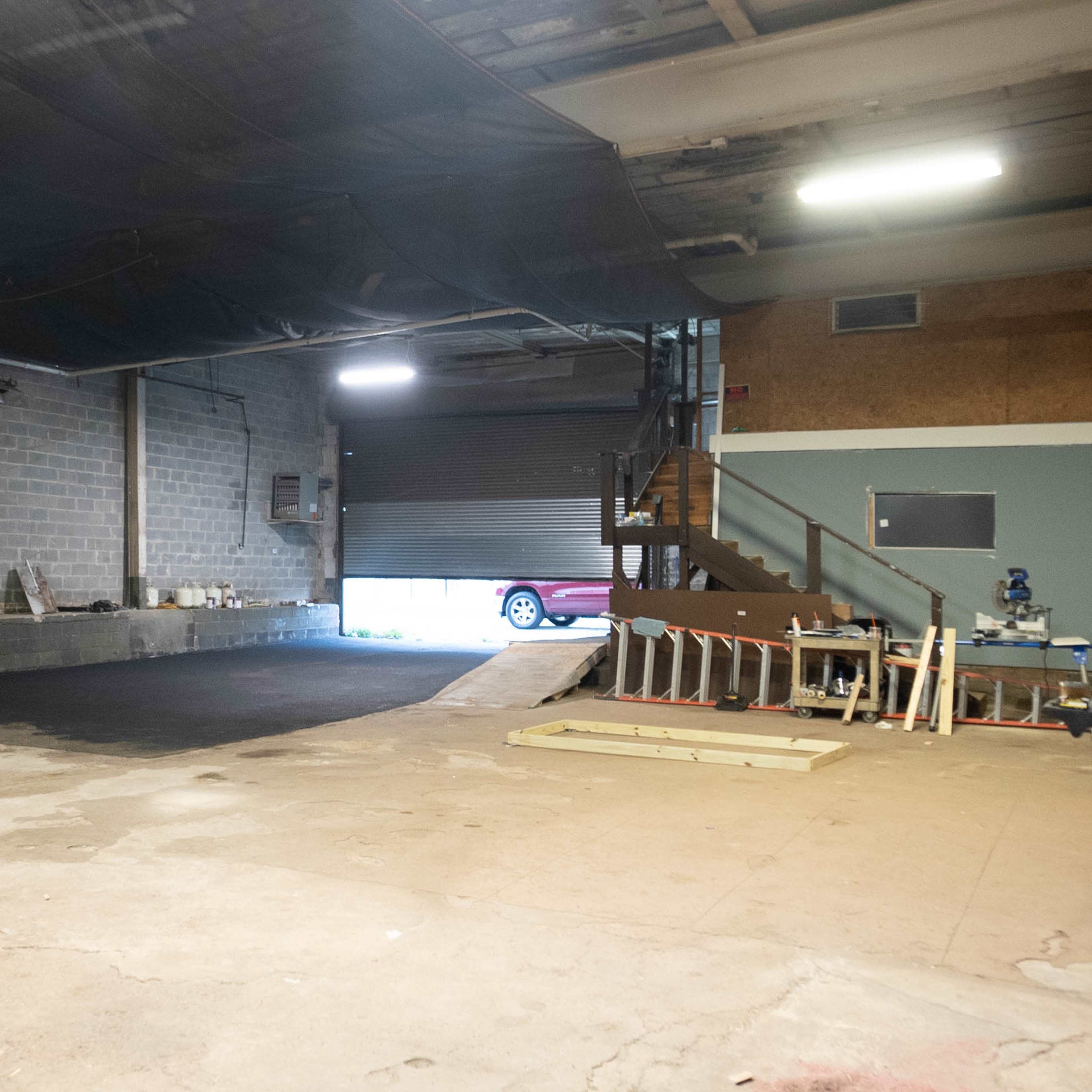 An empty industrial space with a partially completed floor and a loading area that leads to an exterior ramp.