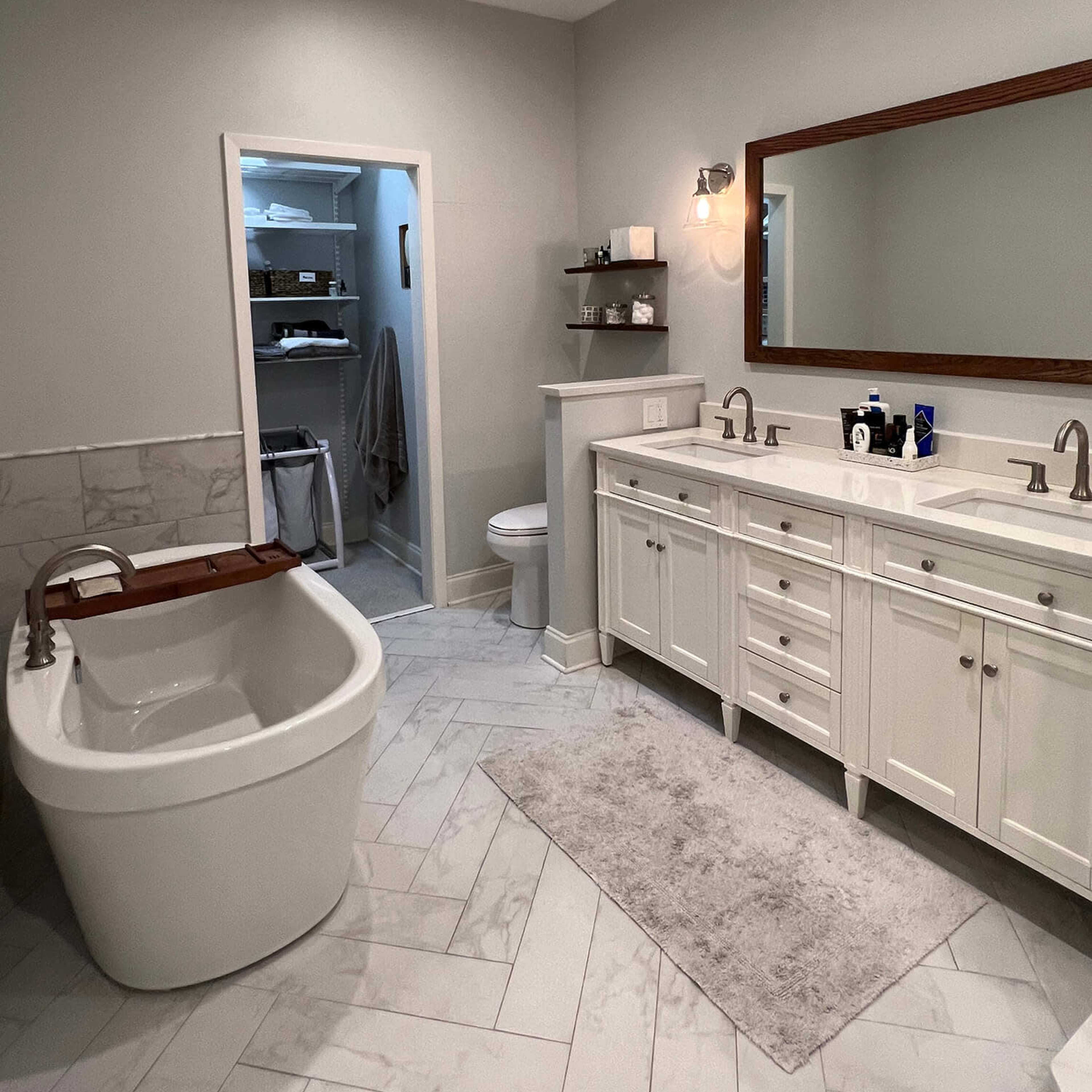 A modern bathroom with a freestanding bathtub, a double sink vanity, and a storage area visible in the far corner.
