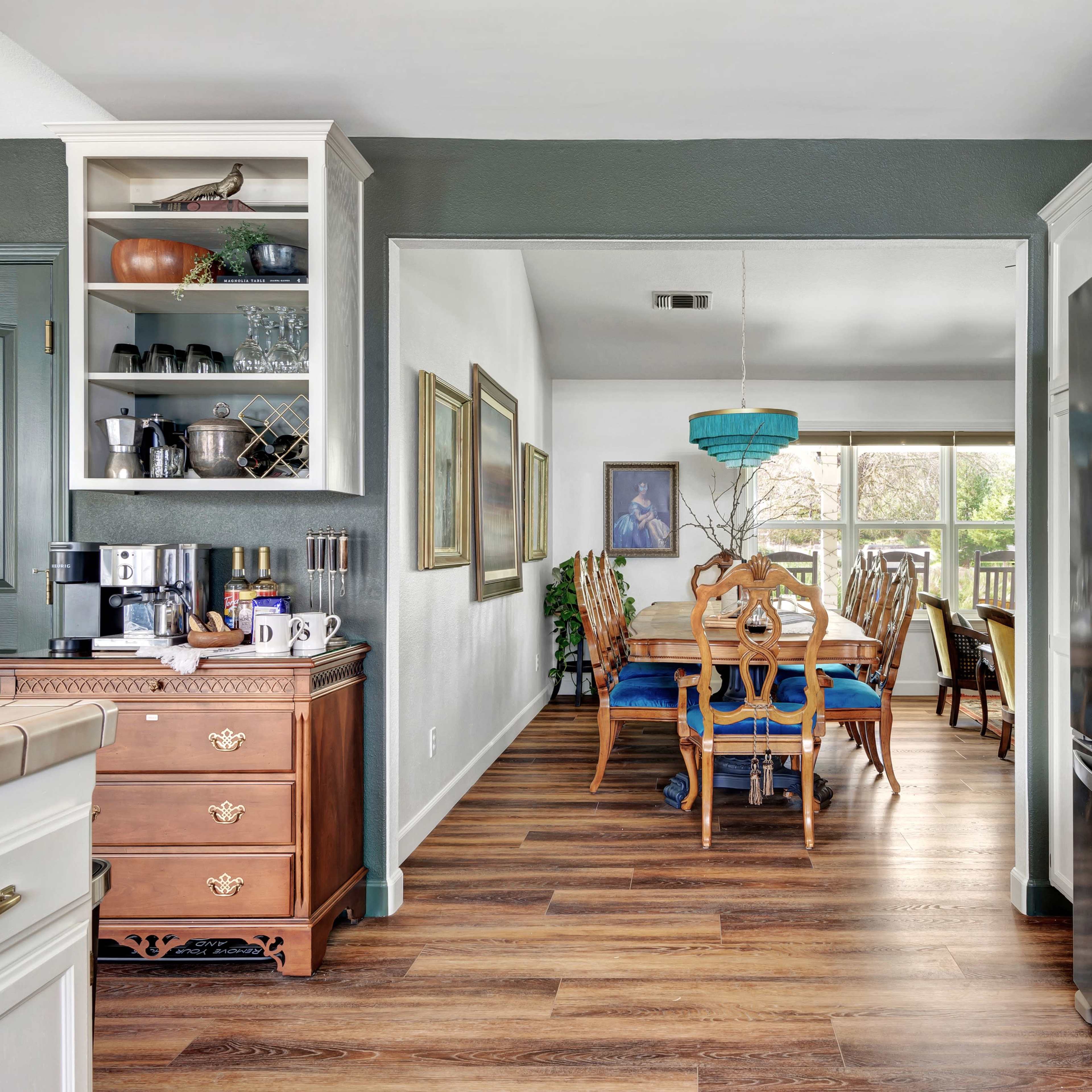 A view of a kitchen leading into a dining area with a wooden dining table and a large window.