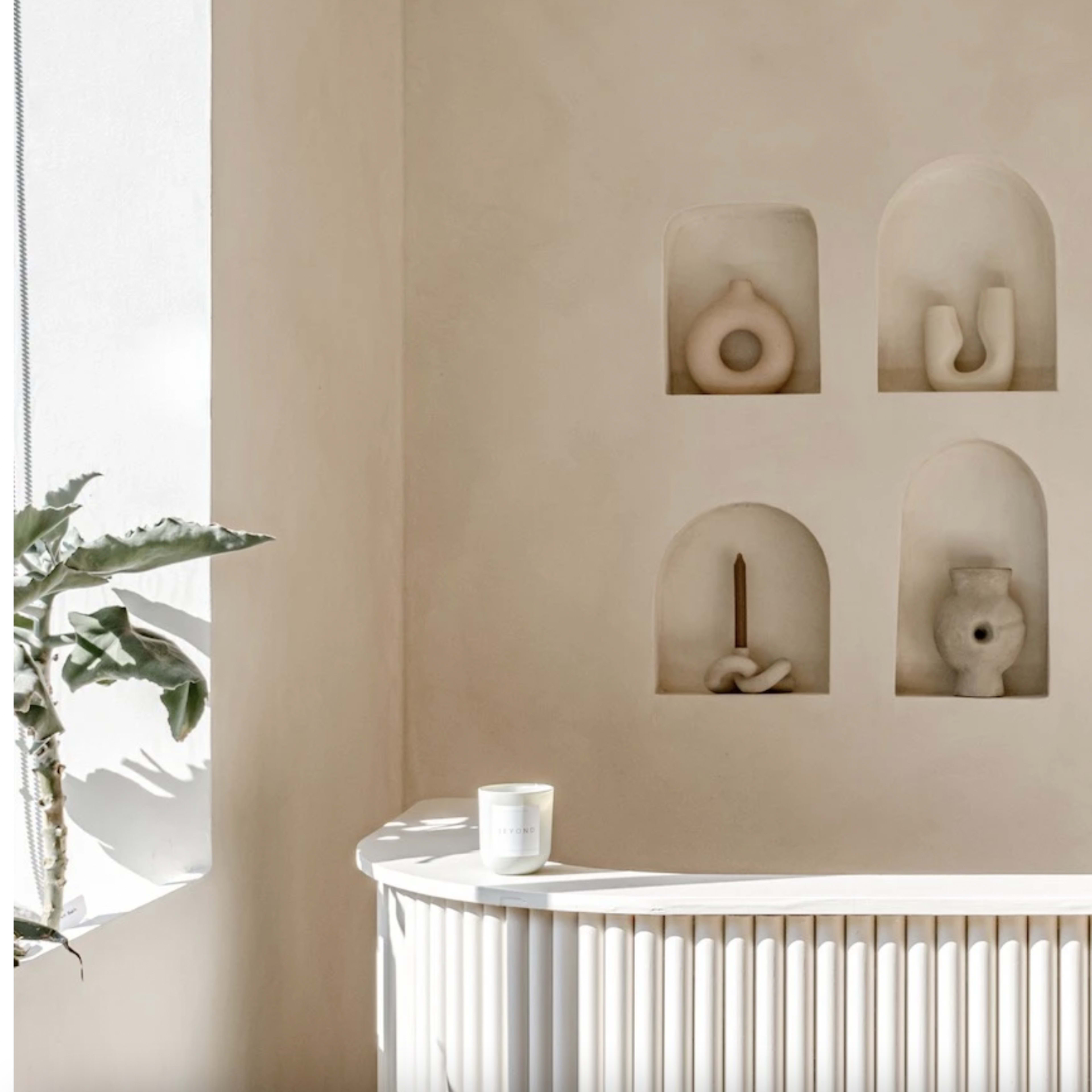 A modern reception area with a curved white counter and six sculptural pieces displayed in recessed alcoves on the wall.