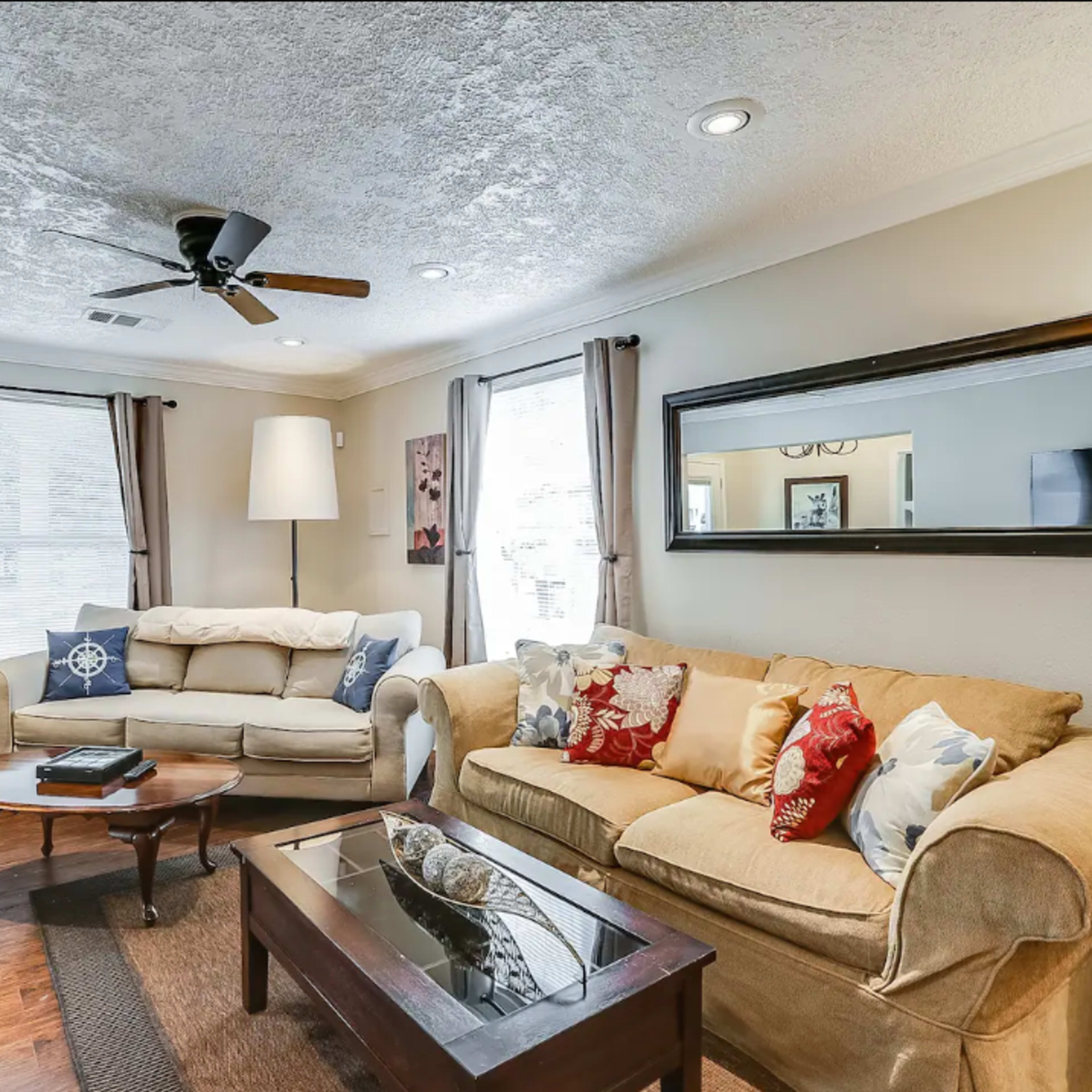 A living room furnished with two sofas, a coffee table, a lamp, and framed artwork on the walls.