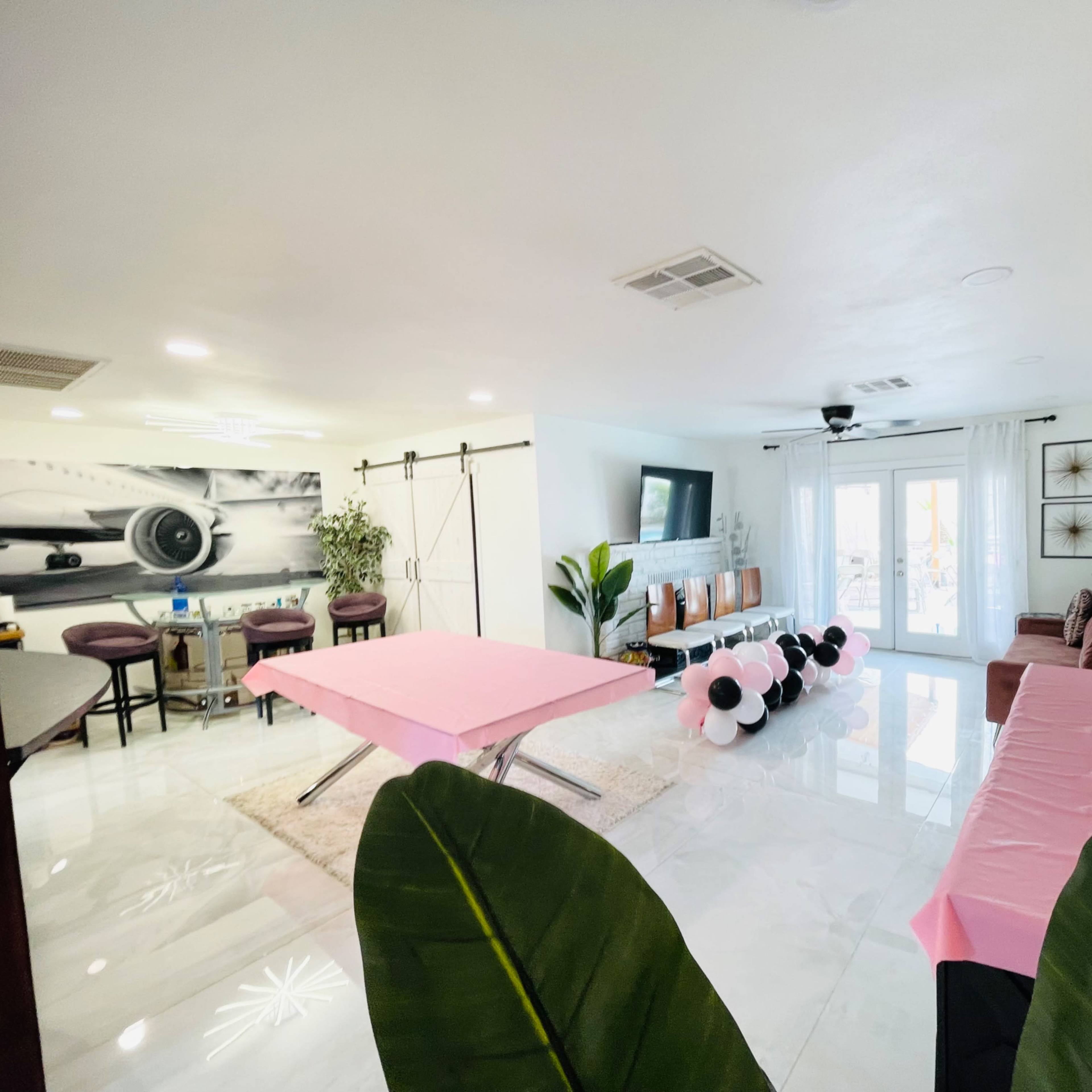 A spacious living area features a pink table and balloon decorations, with sliding doors leading to a patio.