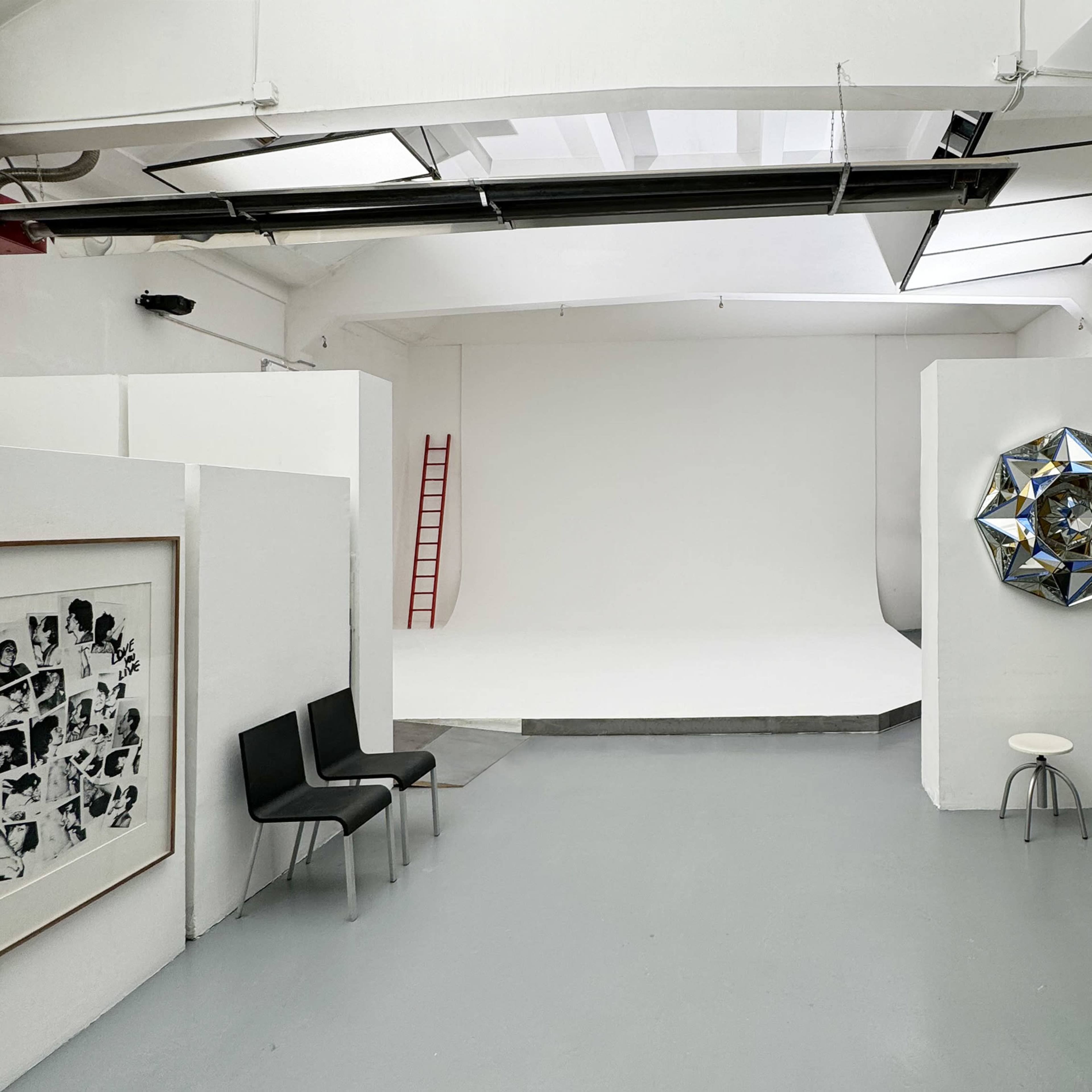 A spacious, minimalist studio with white walls, a simple furniture arrangement, and a clear backdrop for photography.