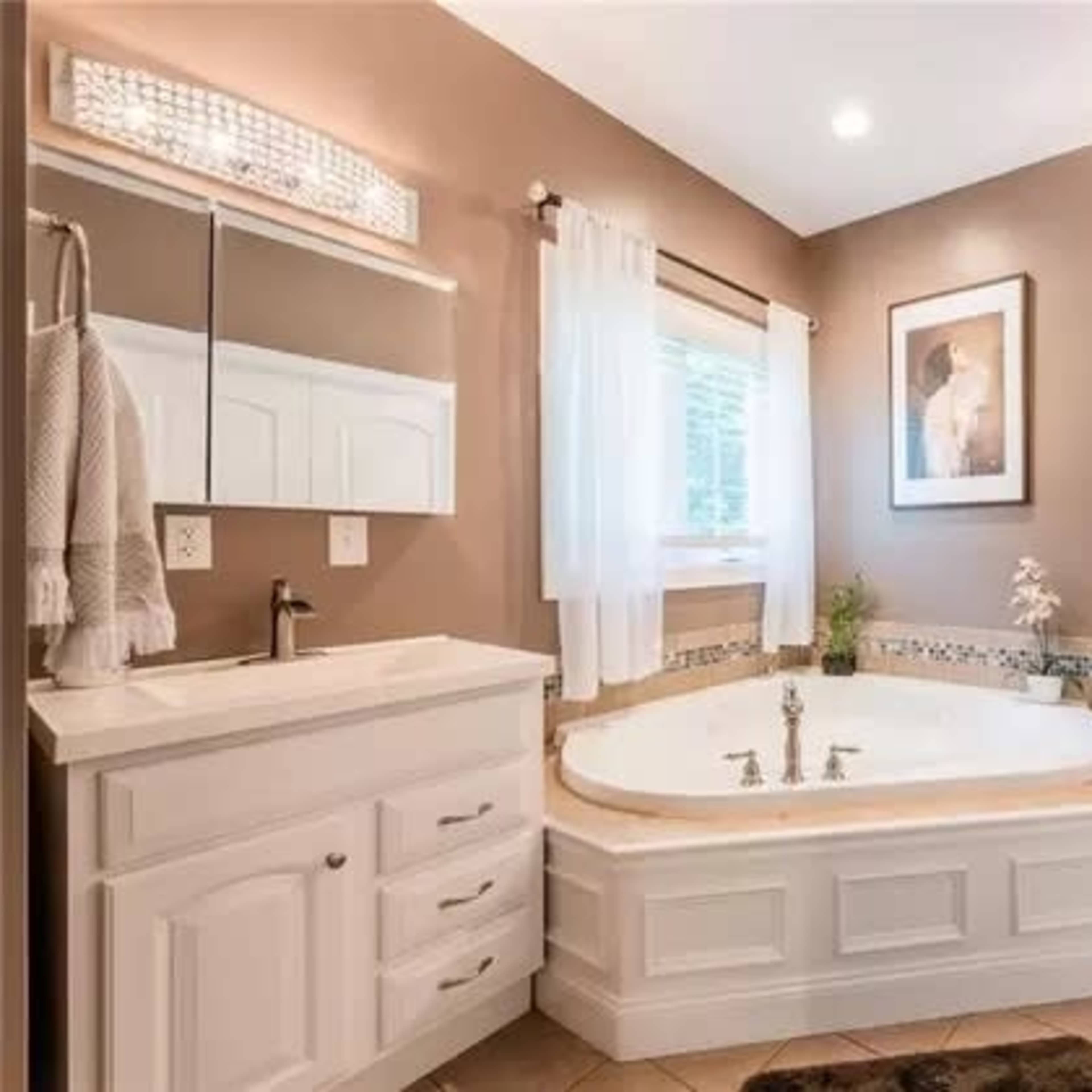 A modern bathroom with a large, curved bathtub, dual sinks, and wall-mounted mirrors, all set against a neutral brown wall.
