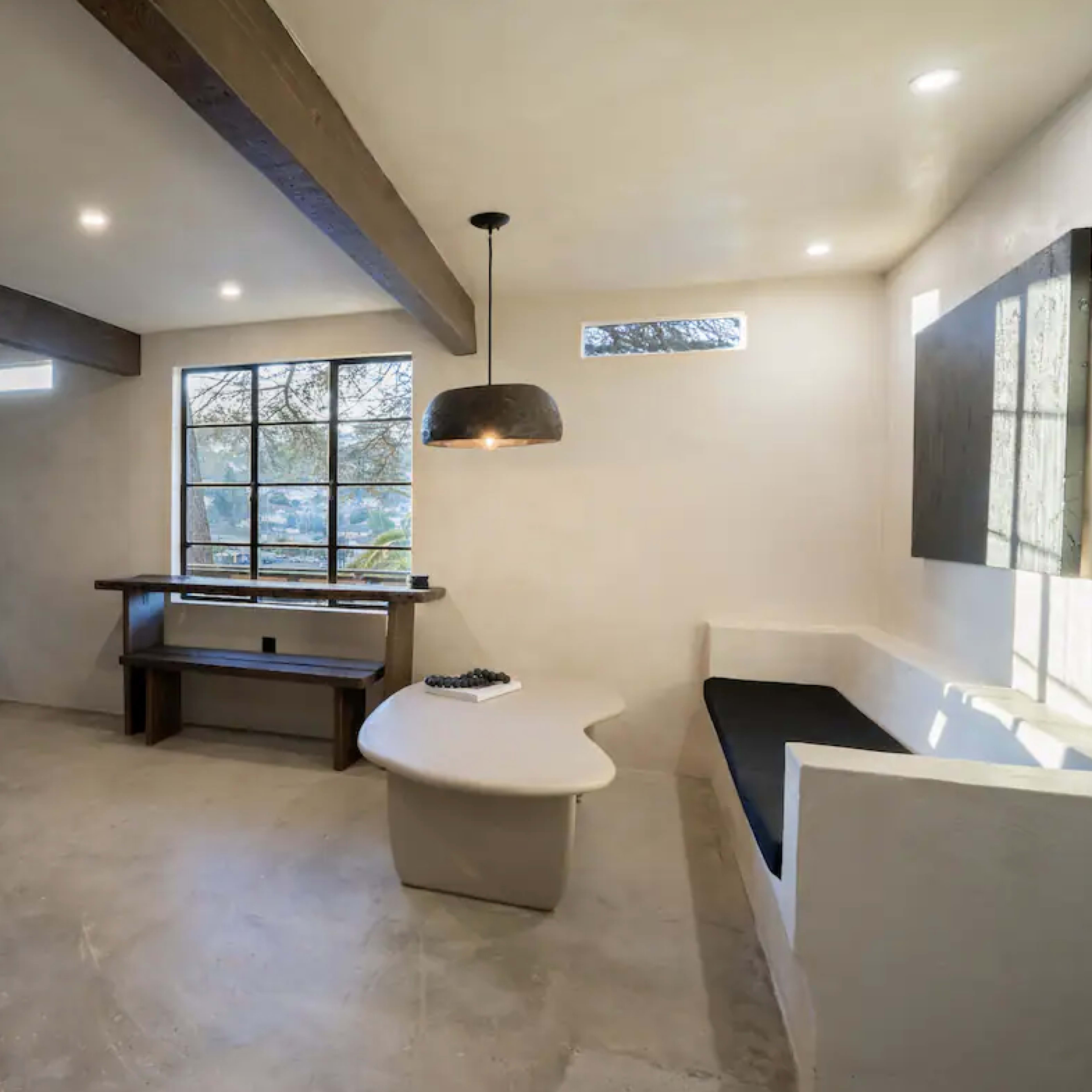 A modern interior living space featuring a neutral color palette, minimalist furniture, and large windows that allow natural light to enter.