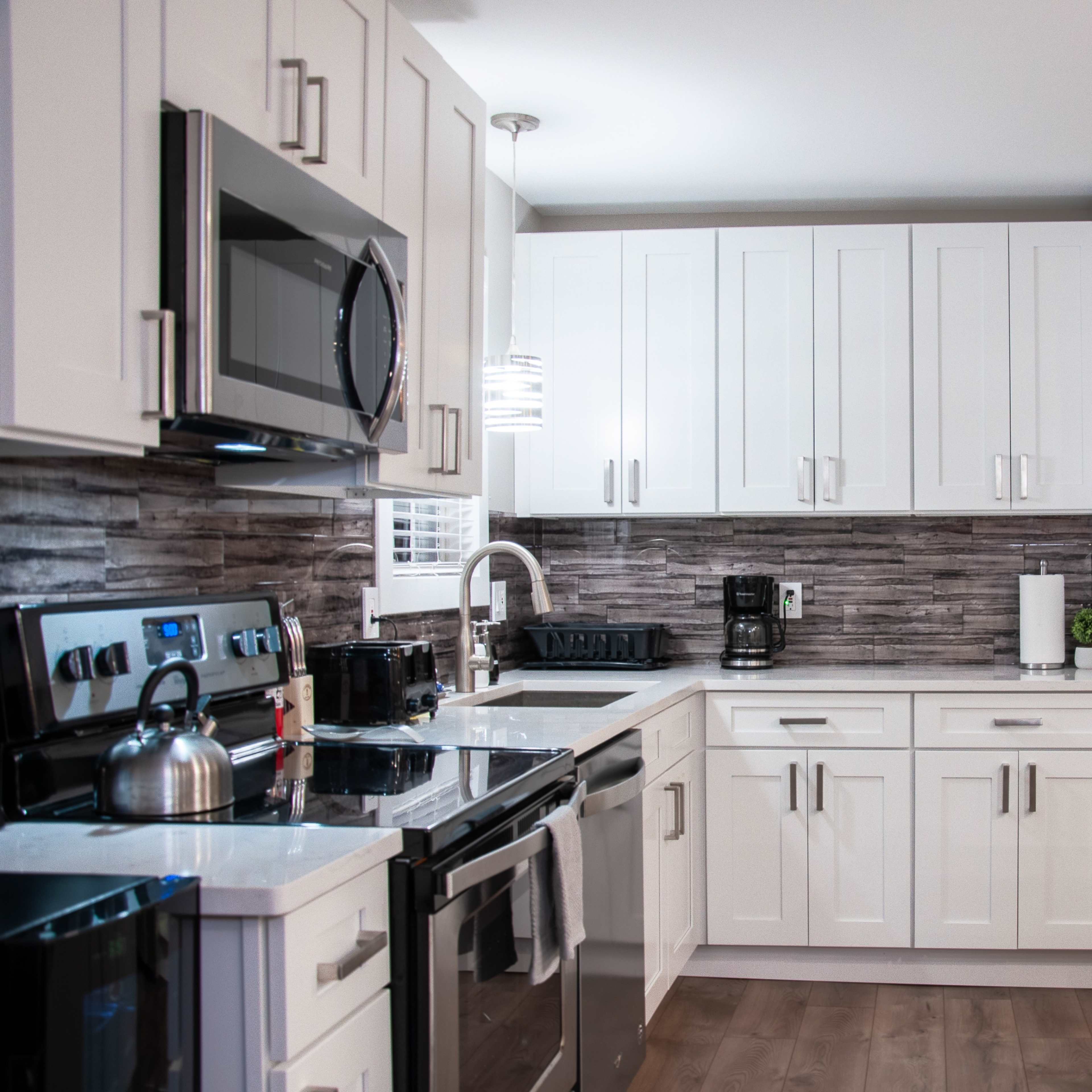 A modern kitchen with white cabinetry, stainless steel appliances, and a central island with a light countertop.