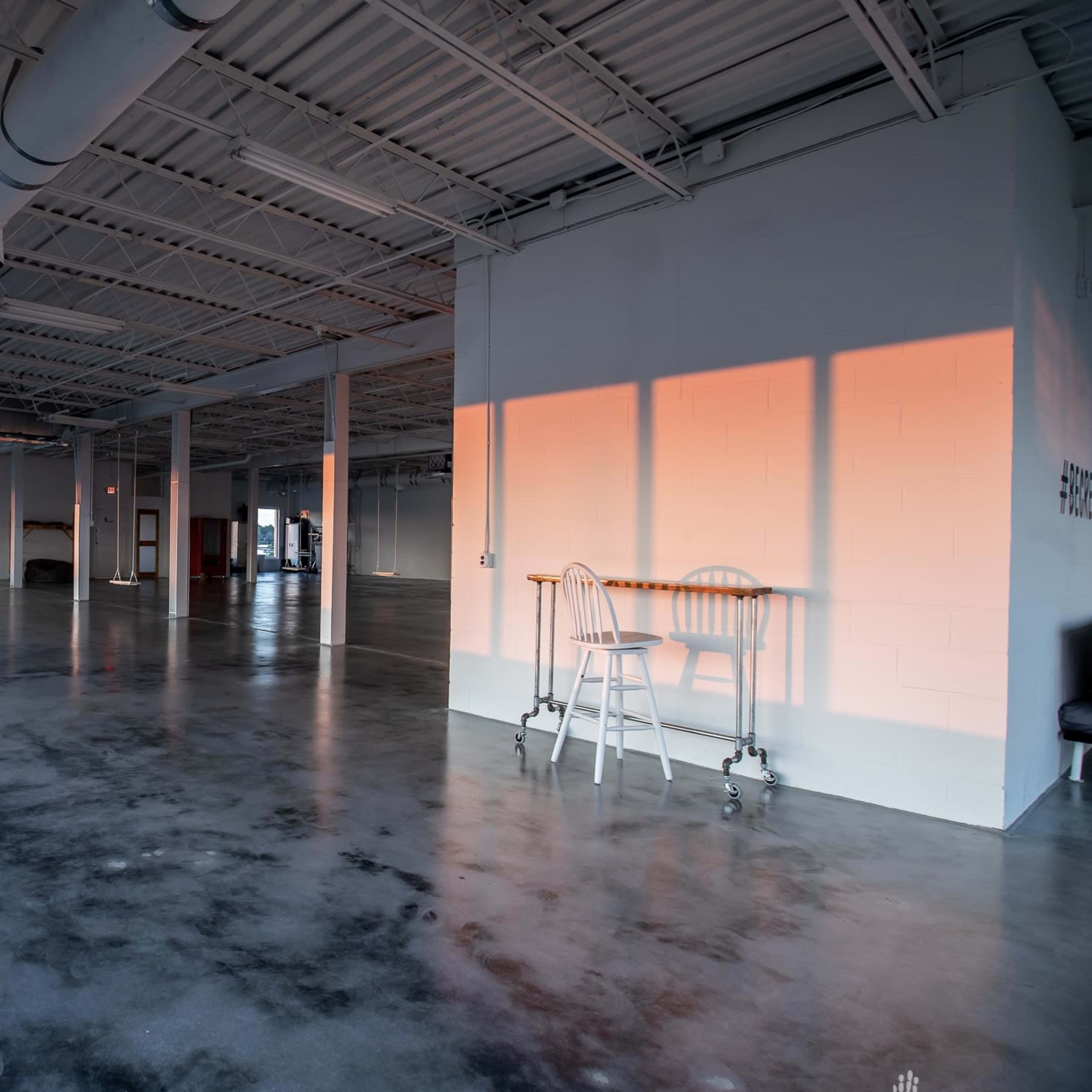 A spacious, empty room with polished concrete floors and large windows allowing natural light to illuminate the interior.
