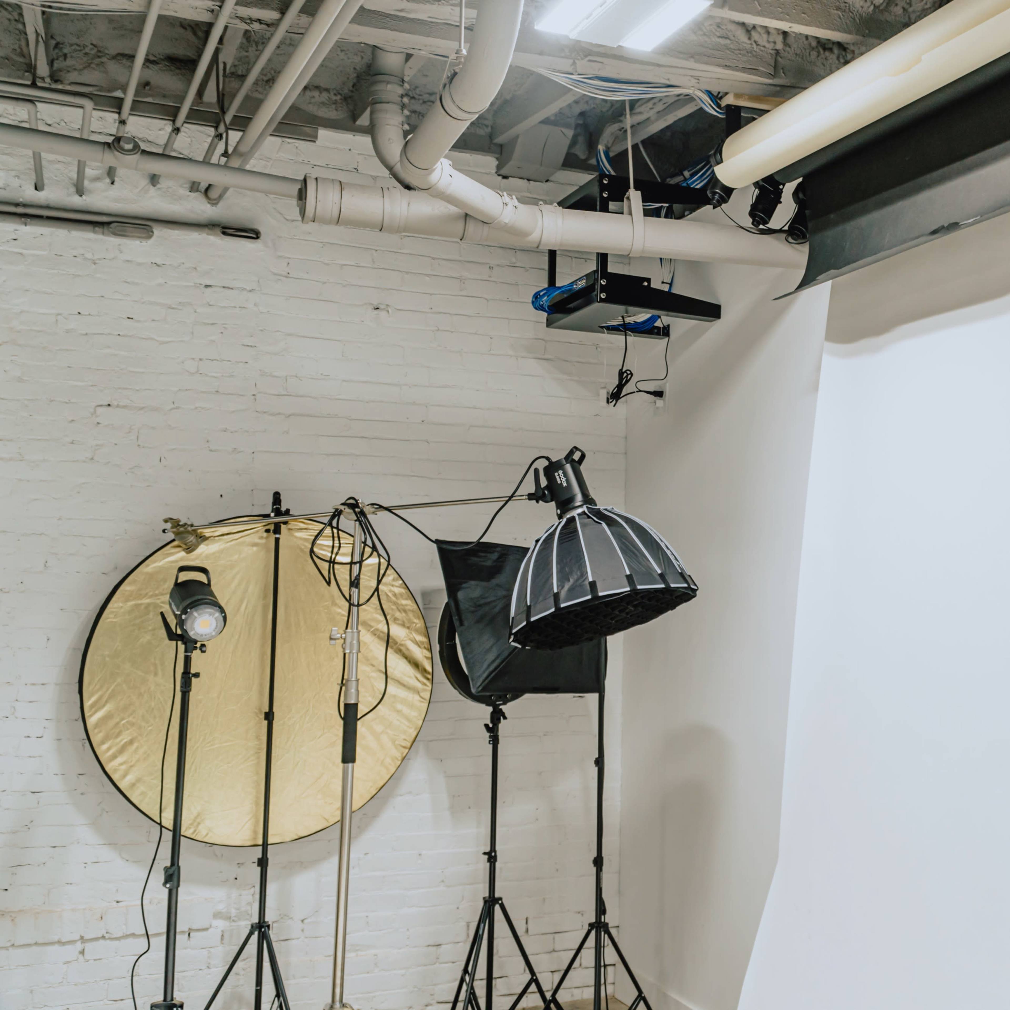A photography studio equipped with a white backdrop, lighting fixtures, and a reflective umbrella.