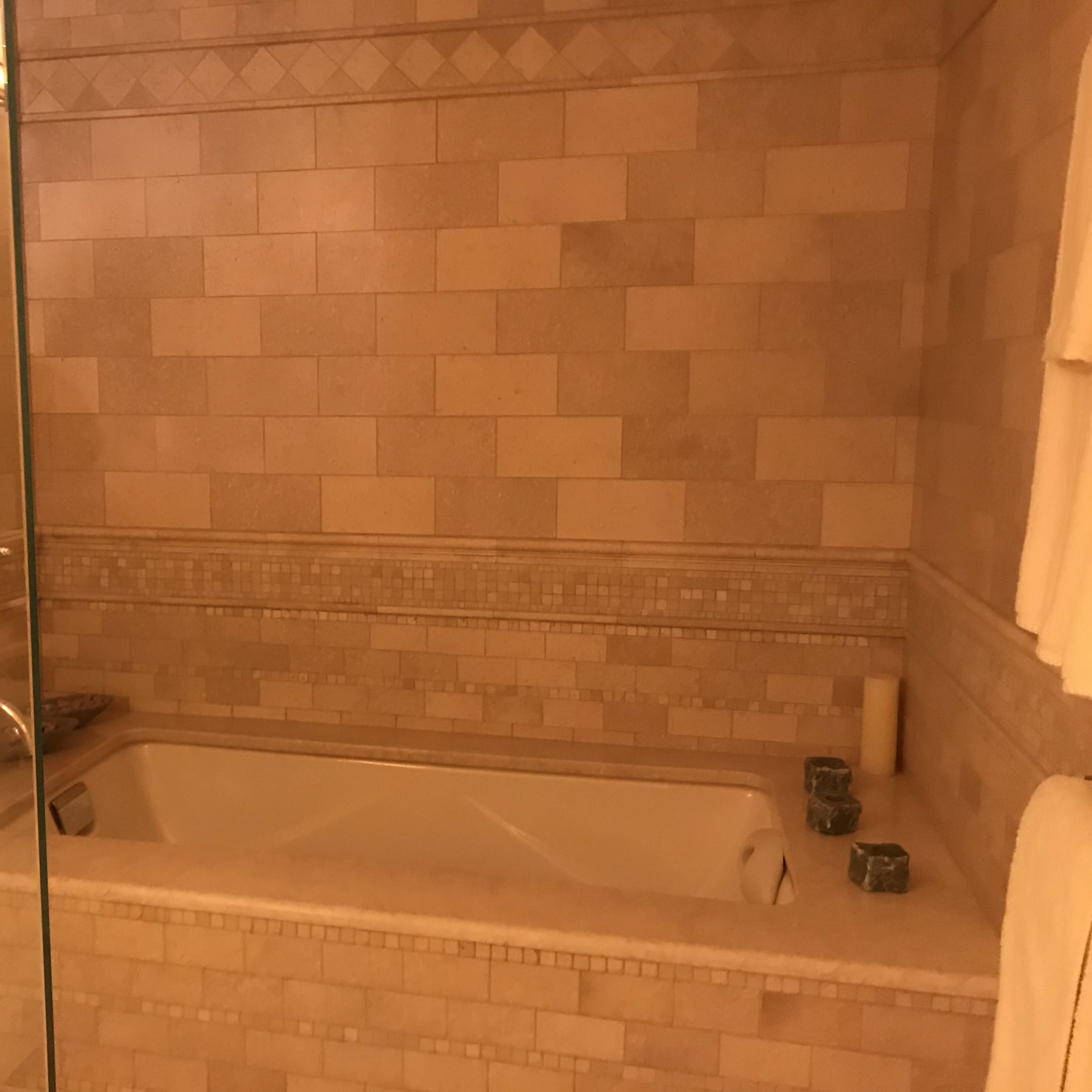 A spacious bathroom featuring a glass-enclosed shower and a bathtub surrounded by tile walls.