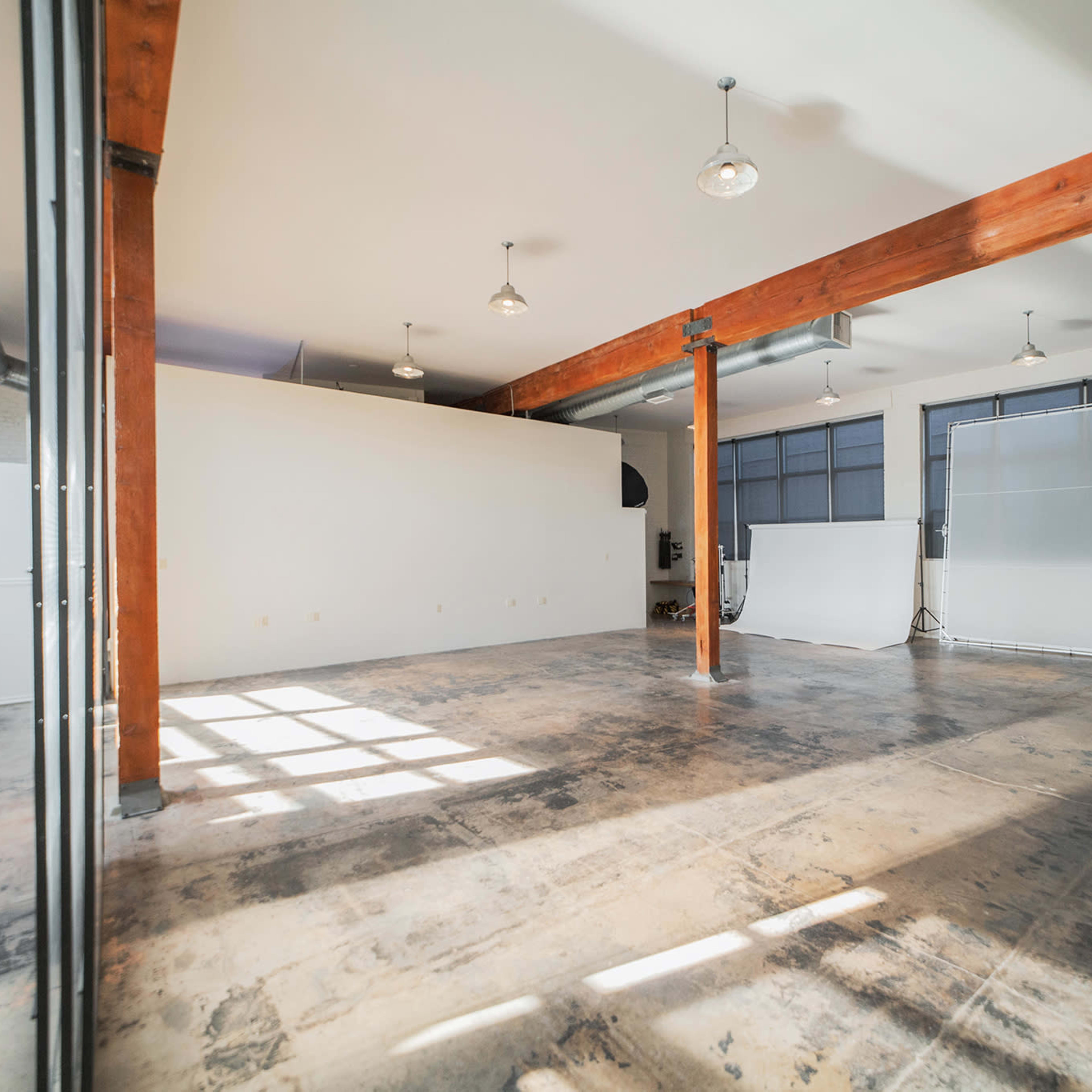 A spacious, industrial-style interior with polished concrete floors, large windows, and wooden beams.