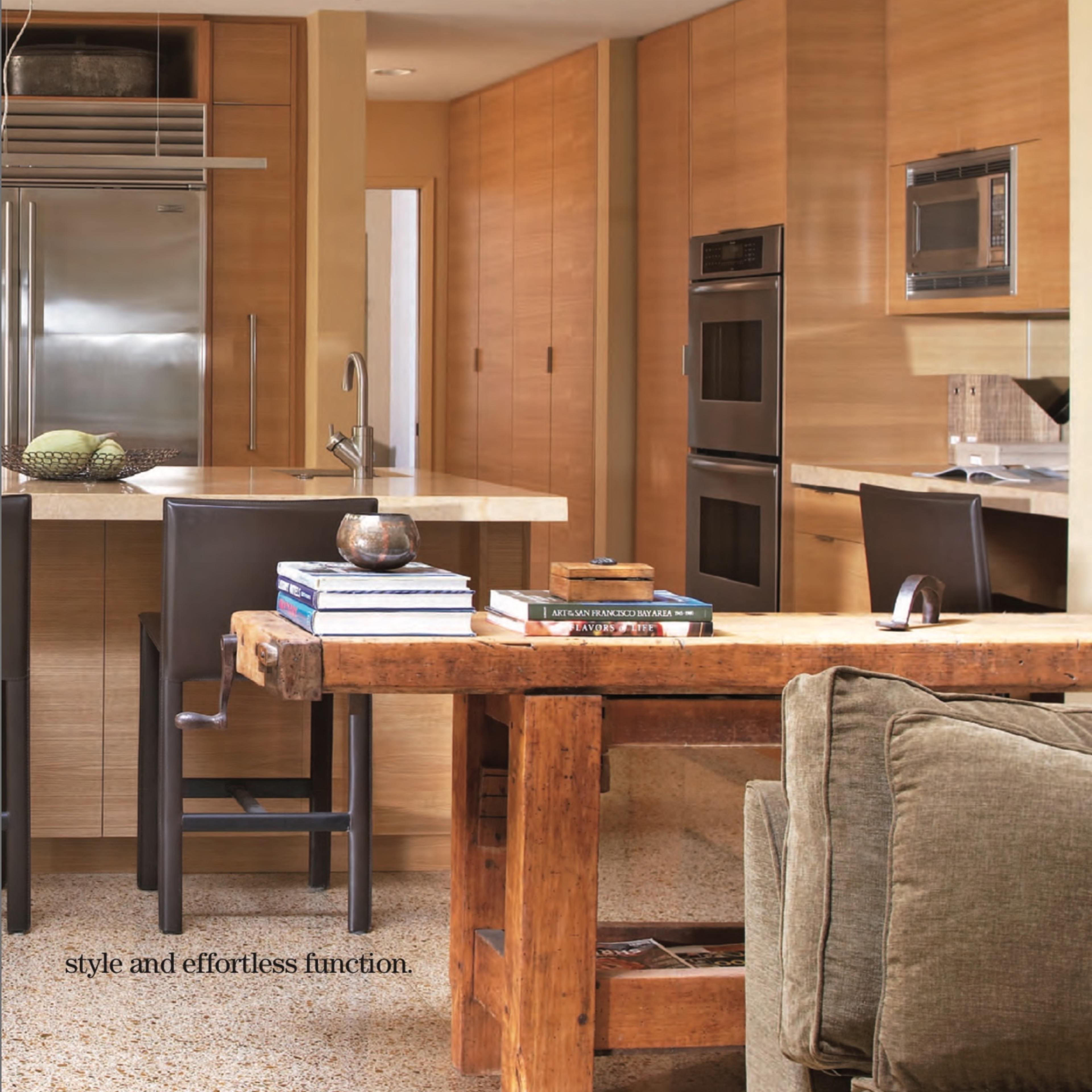 A modern kitchen with wooden cabinetry, stainless steel appliances, and a dining area featuring a large wooden table and chairs.
