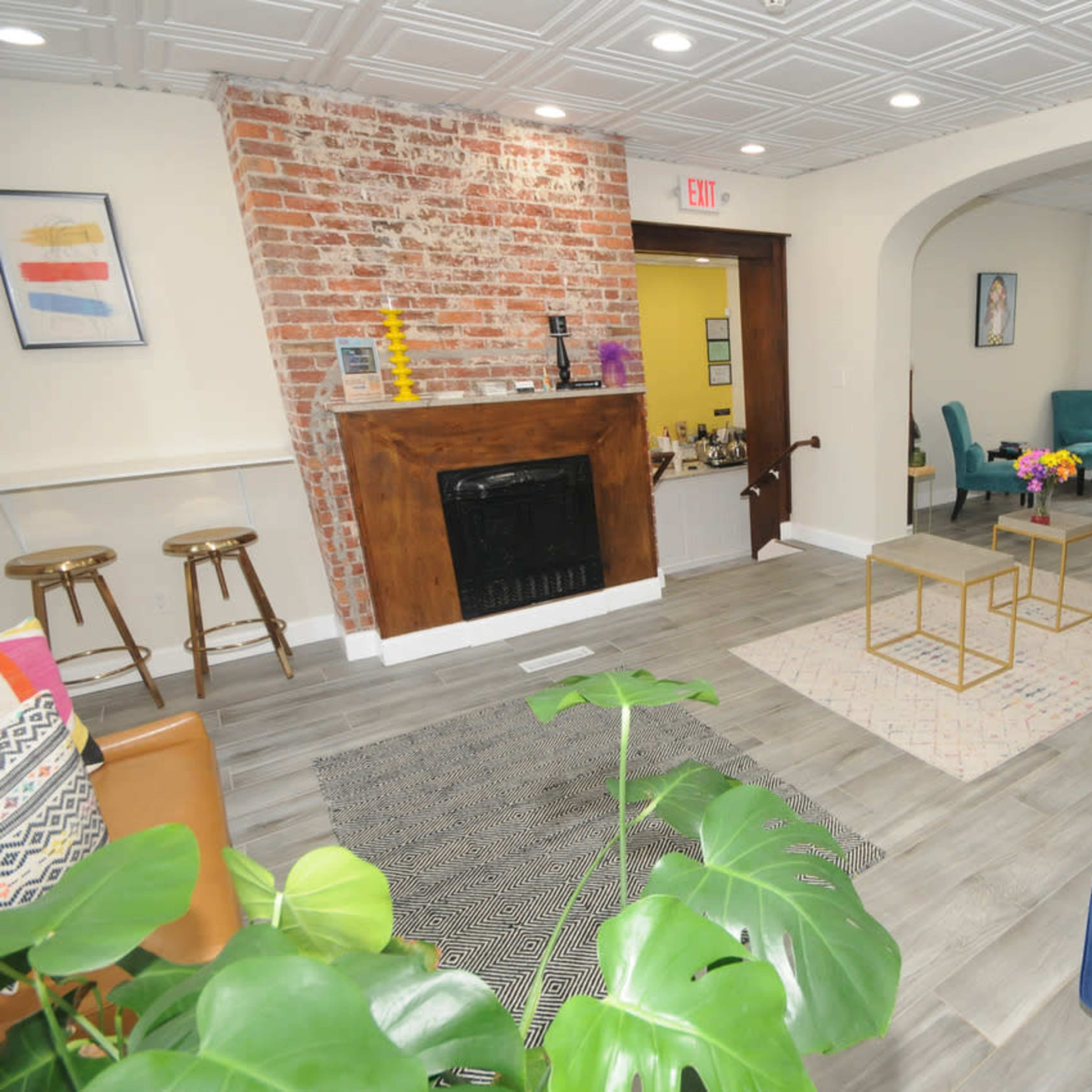 A welcoming lounge area featuring a blue sofa, a wooden bar with stools, and a seating arrangement with colorful chairs and a coffee table.
