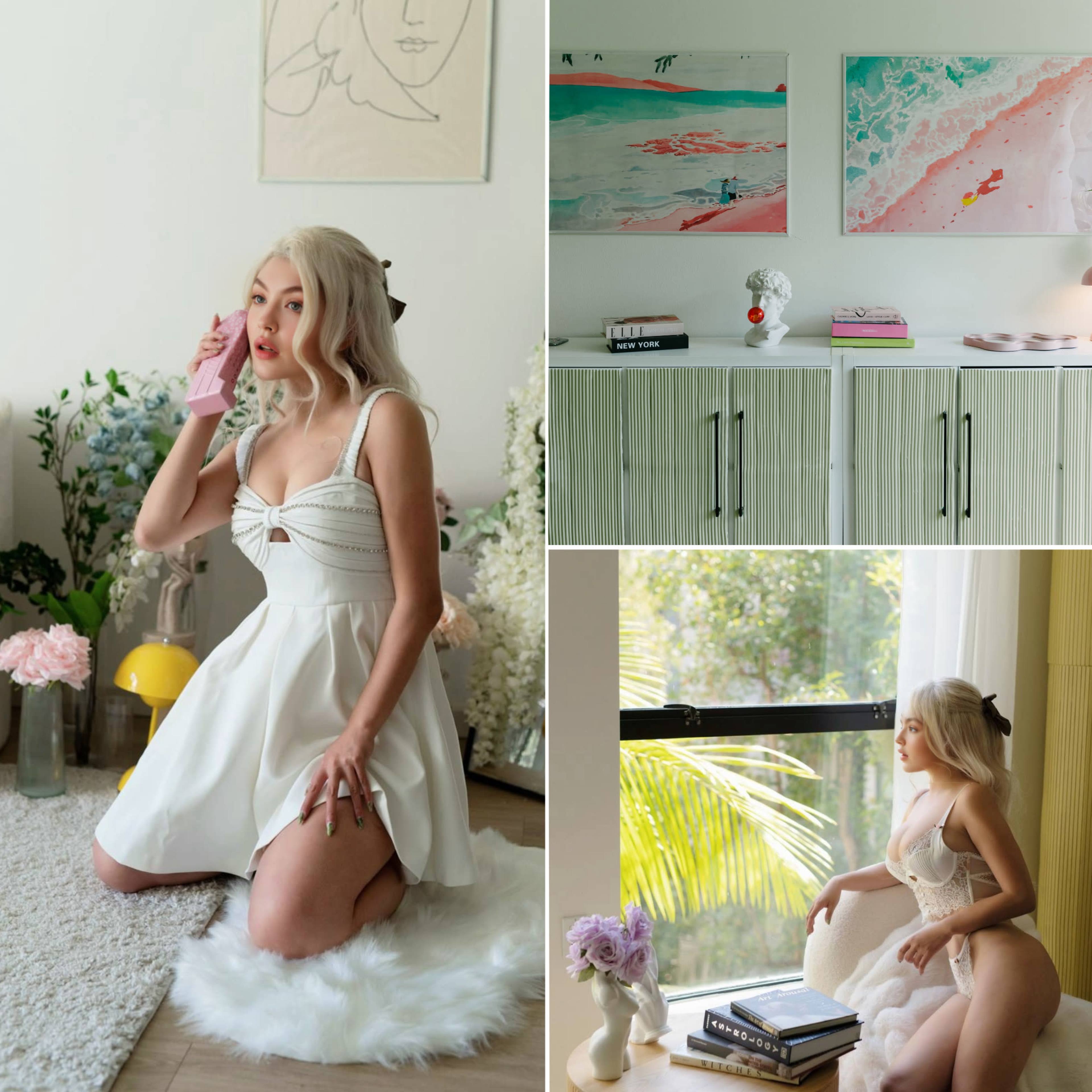 A woman in a white dress posing in a bright room with colorful artwork on the walls.