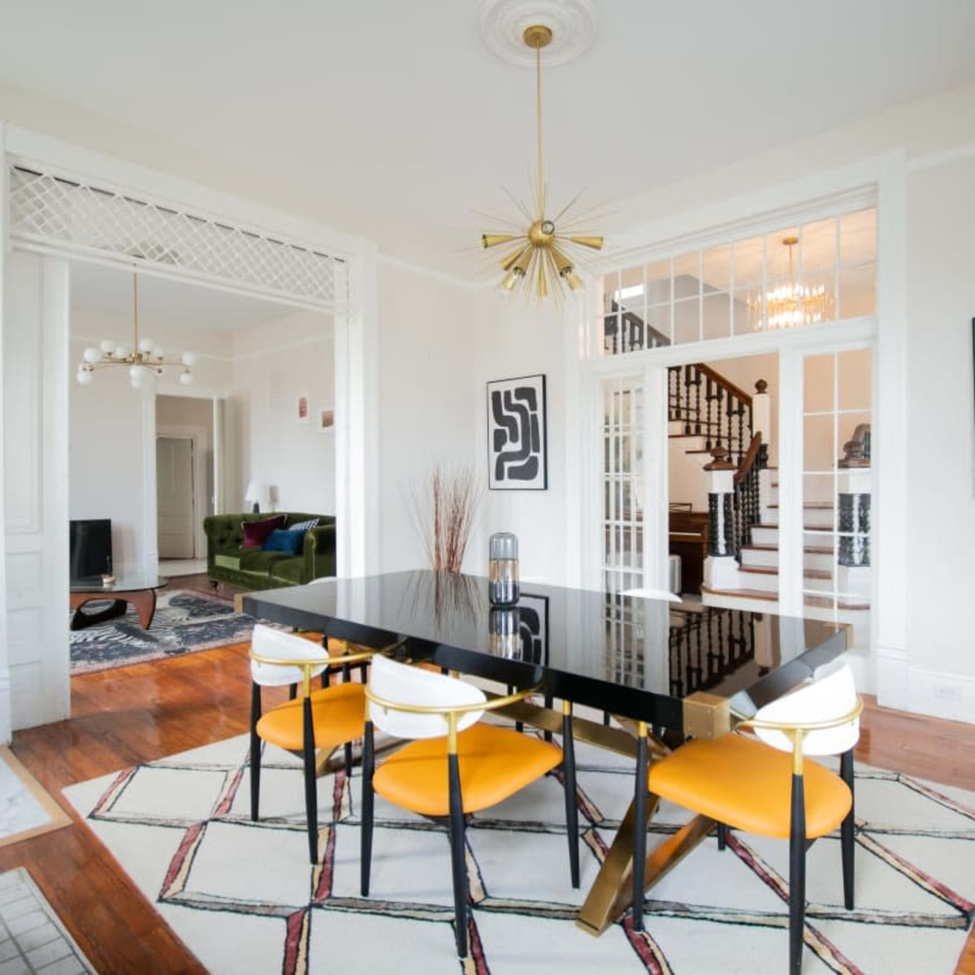 A modern dining area features a black table with yellow chairs, surrounded by stylish decor and an open view into a well-lit living space.