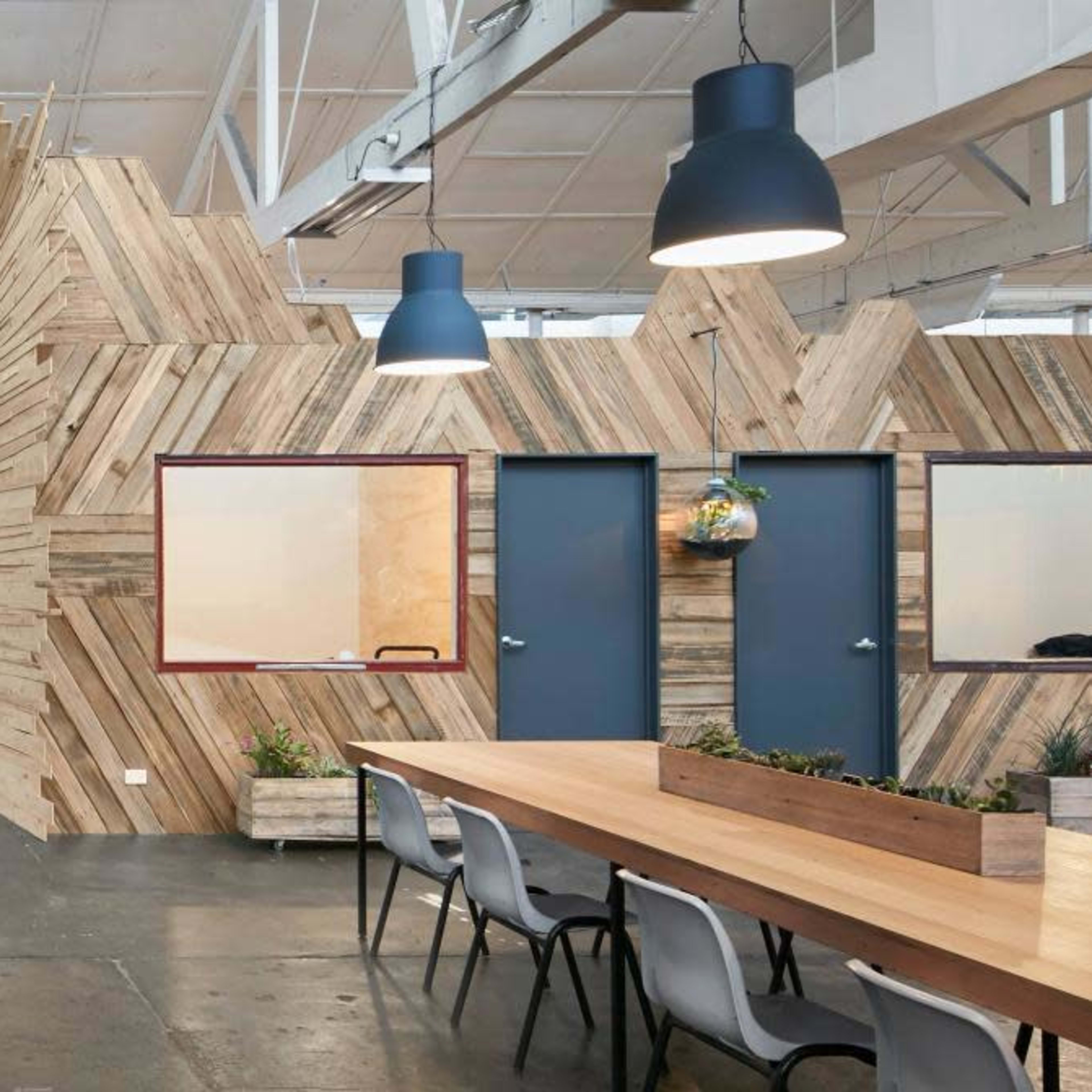 An open office space featuring wooden paneling, a couch area, and several doorways leading to different rooms.