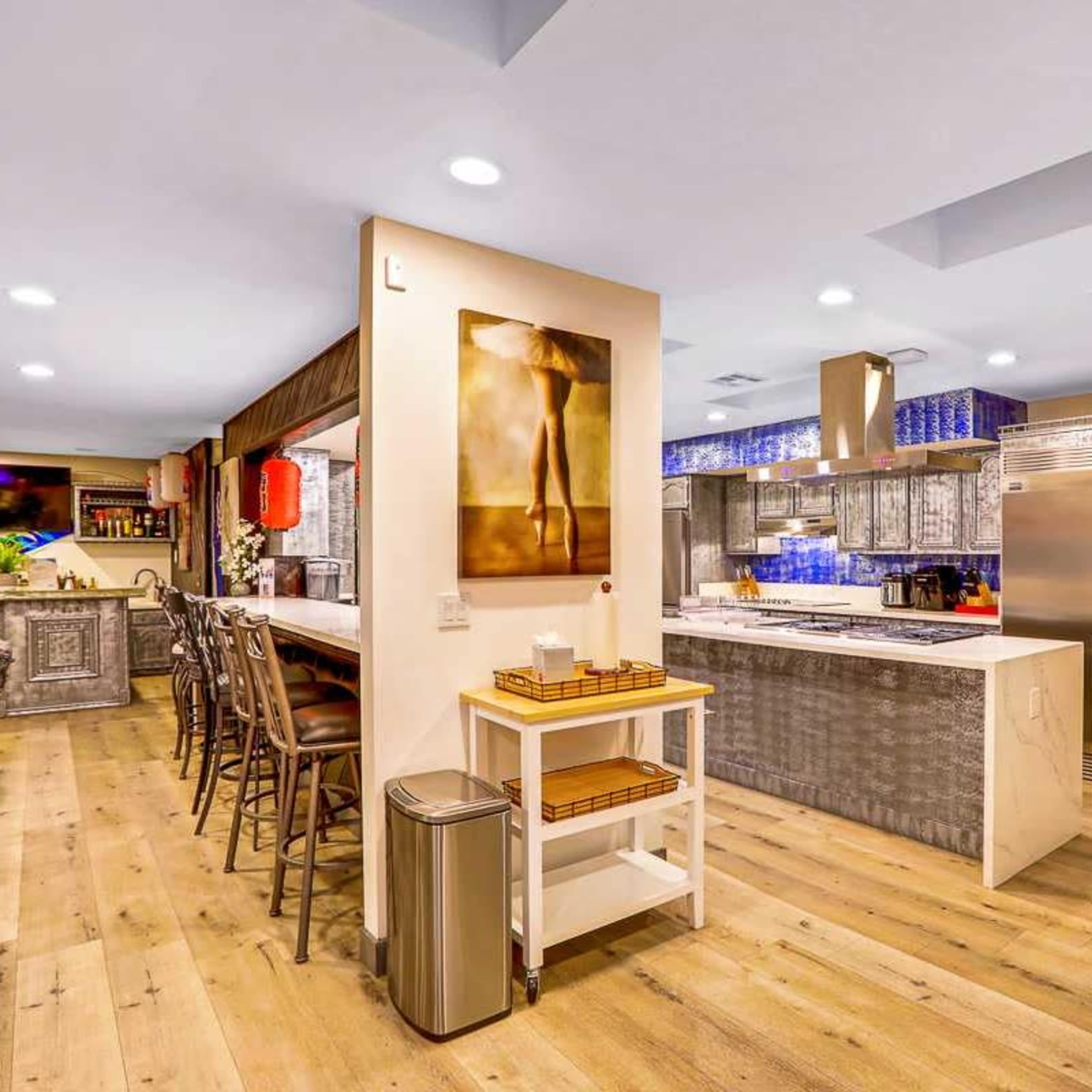 The kitchen features modern appliances, a central island, and wooden flooring with a decorative backsplash.