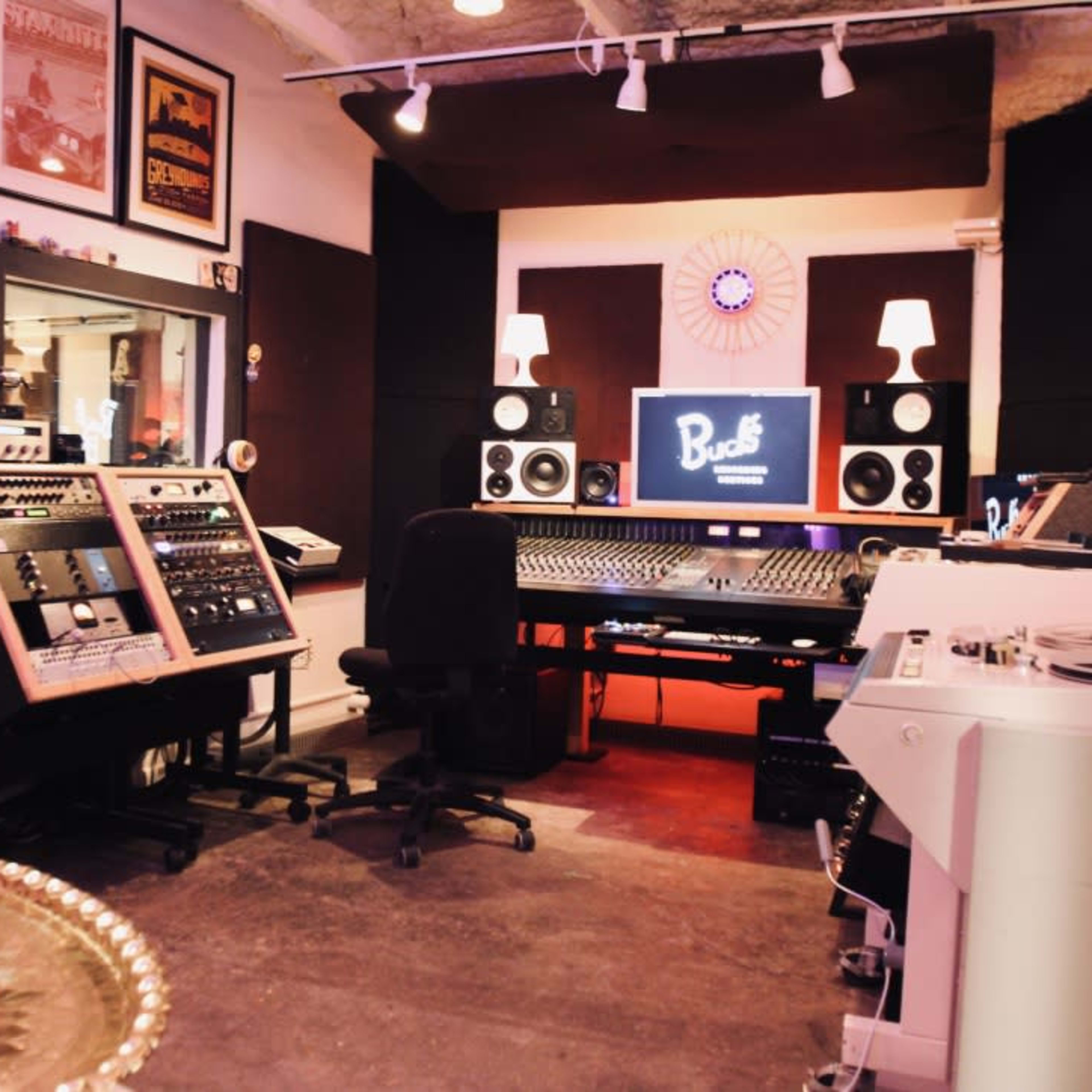 A music recording studio with a control desk, audio equipment, and soundproofing panels on the walls.