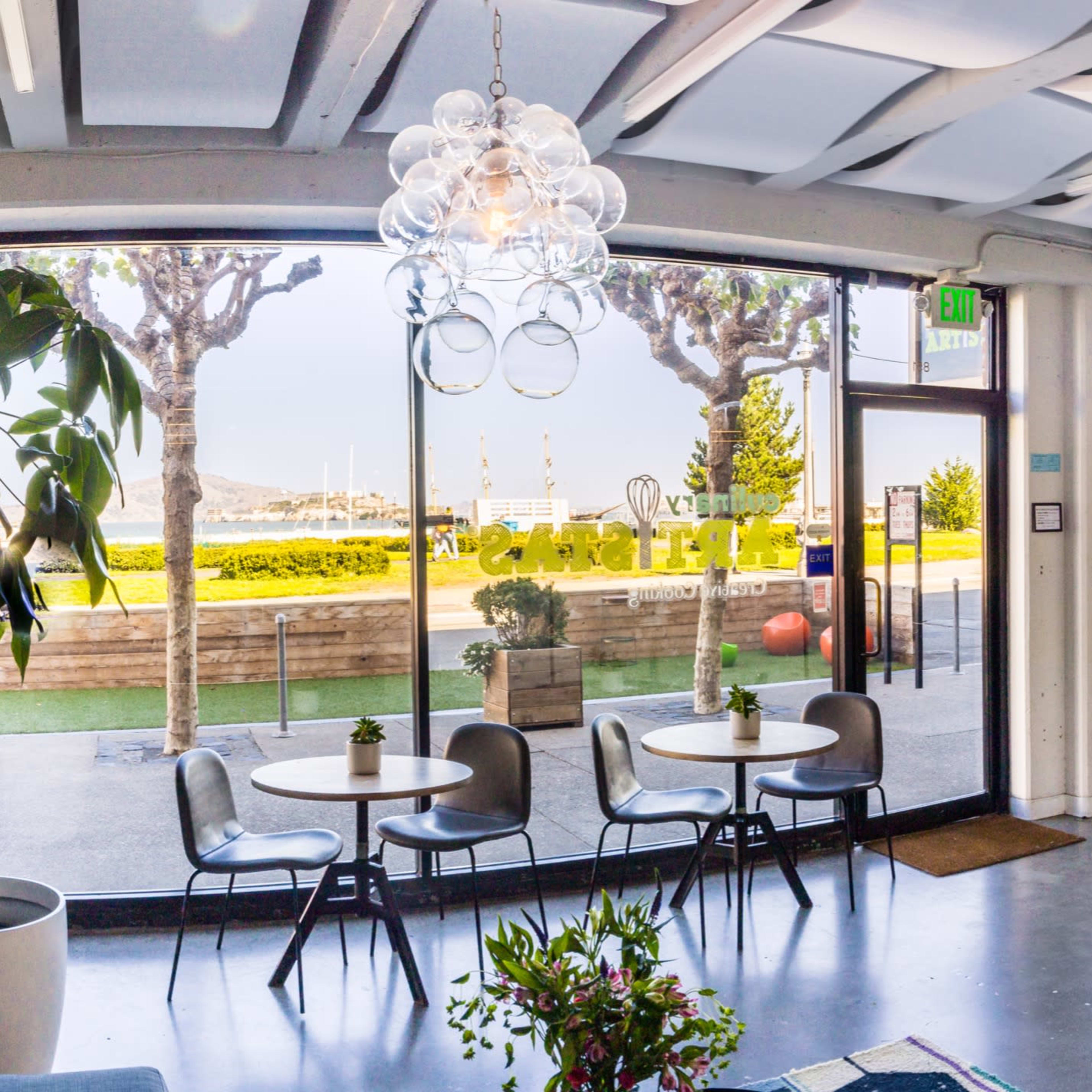 A modern interior space with a seating area, large windows overlooking an outdoor landscape, and decorative plants.