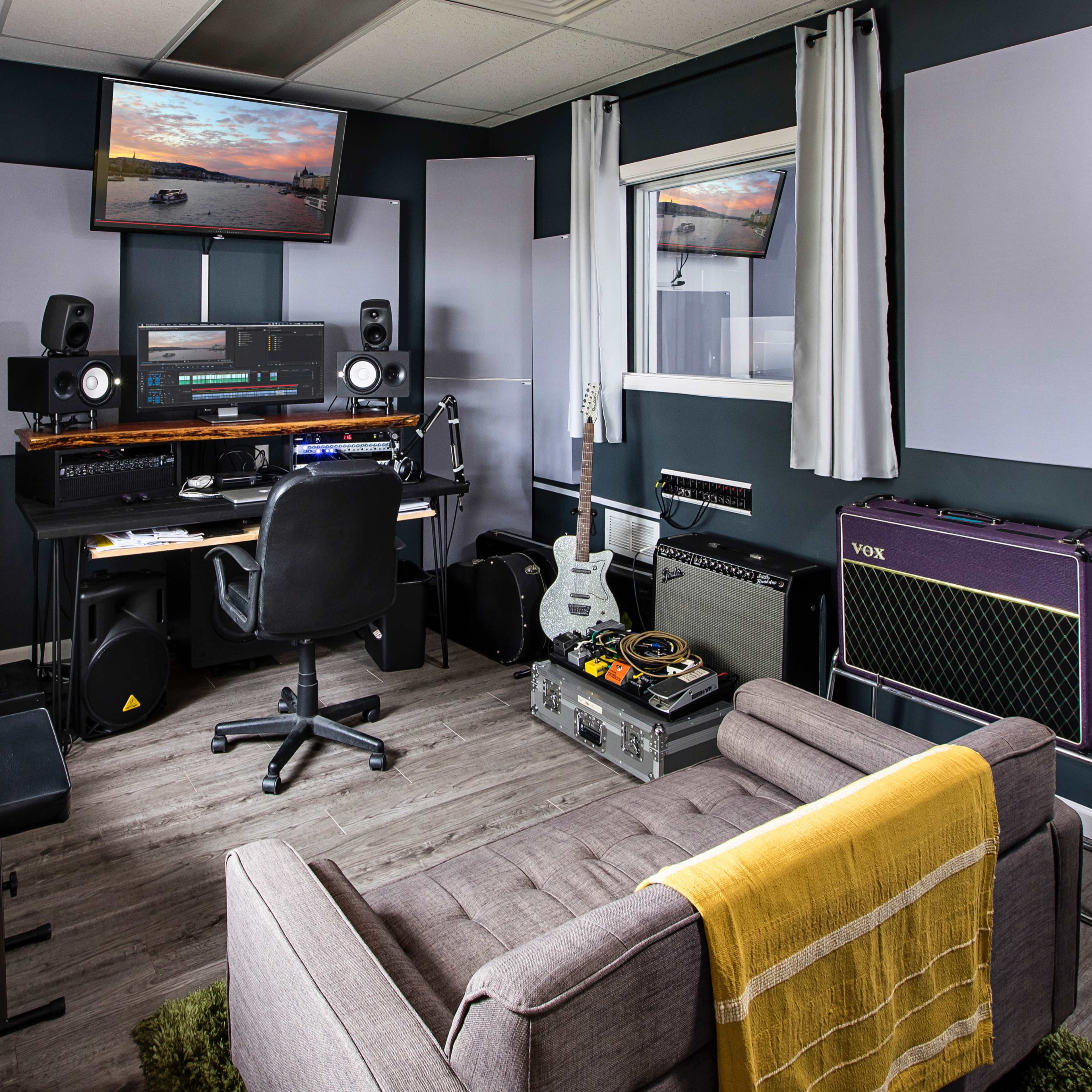 A modern music studio with a keyboard, audio equipment, and seating arranged around a central workspace.