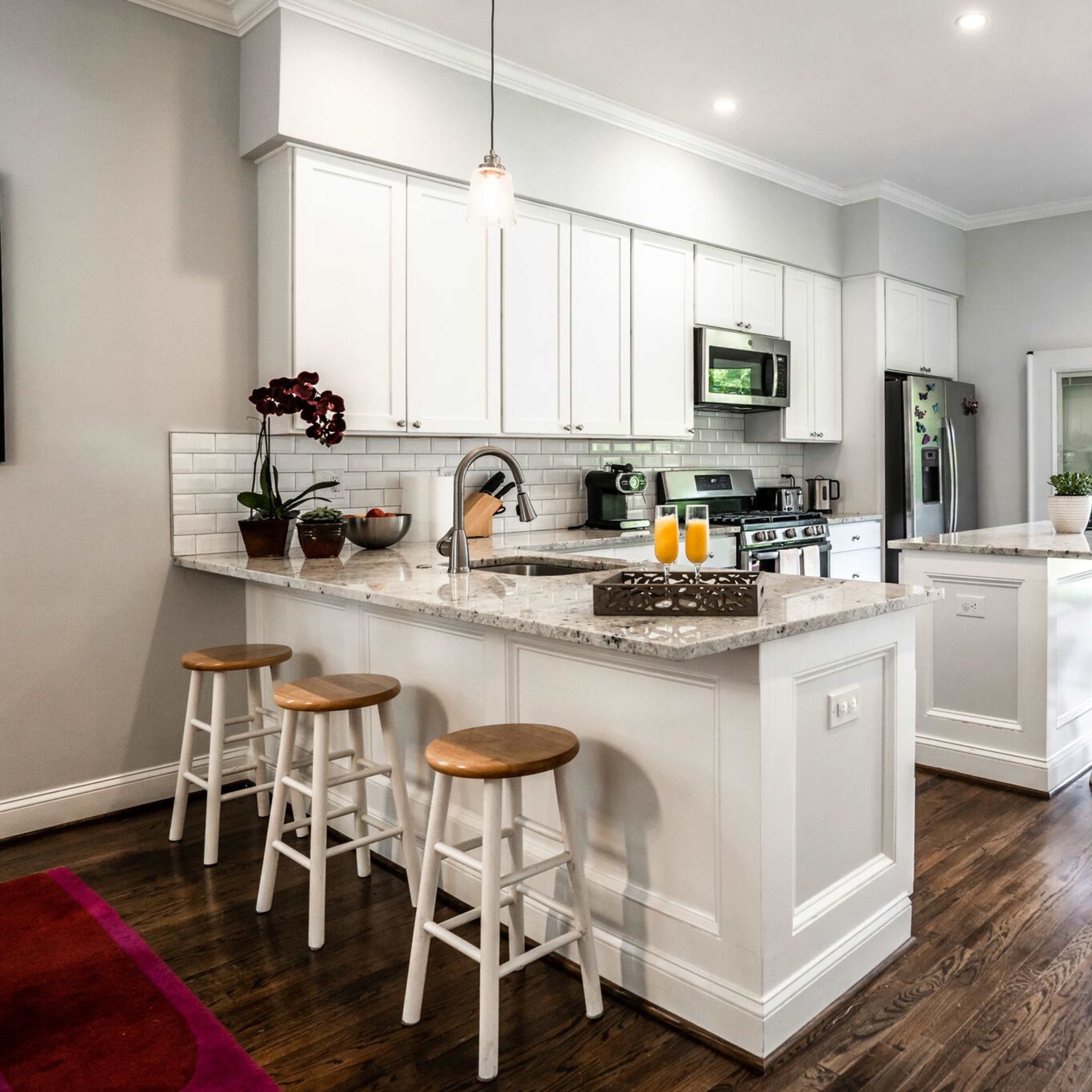 A modern kitchen with white cabinets, stainless steel appliances, a granite countertop island, and a doorway leading to an outdoor patio.