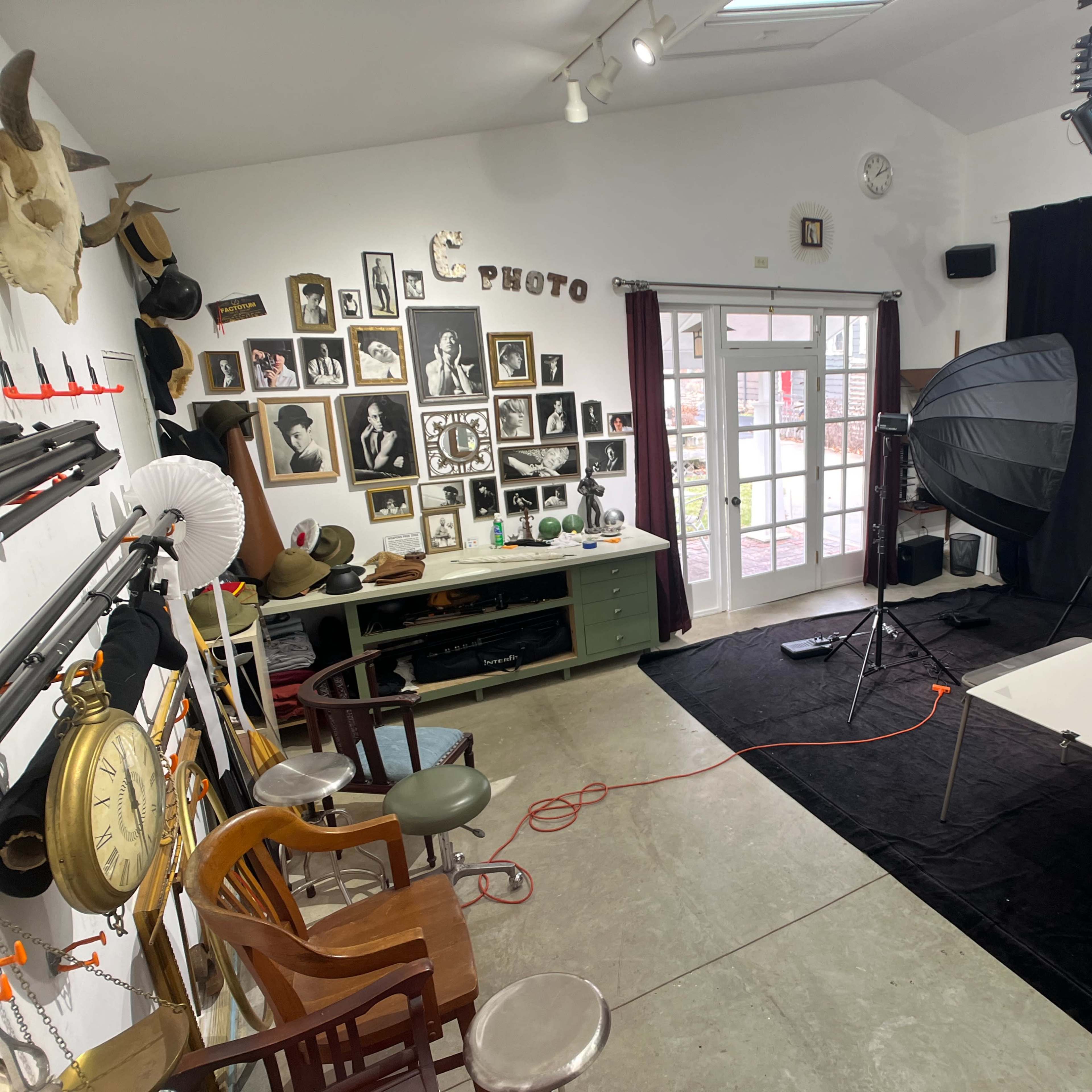 A photography studio features a backdrop, lighting equipment, and a collection of framed photographs on the wall.