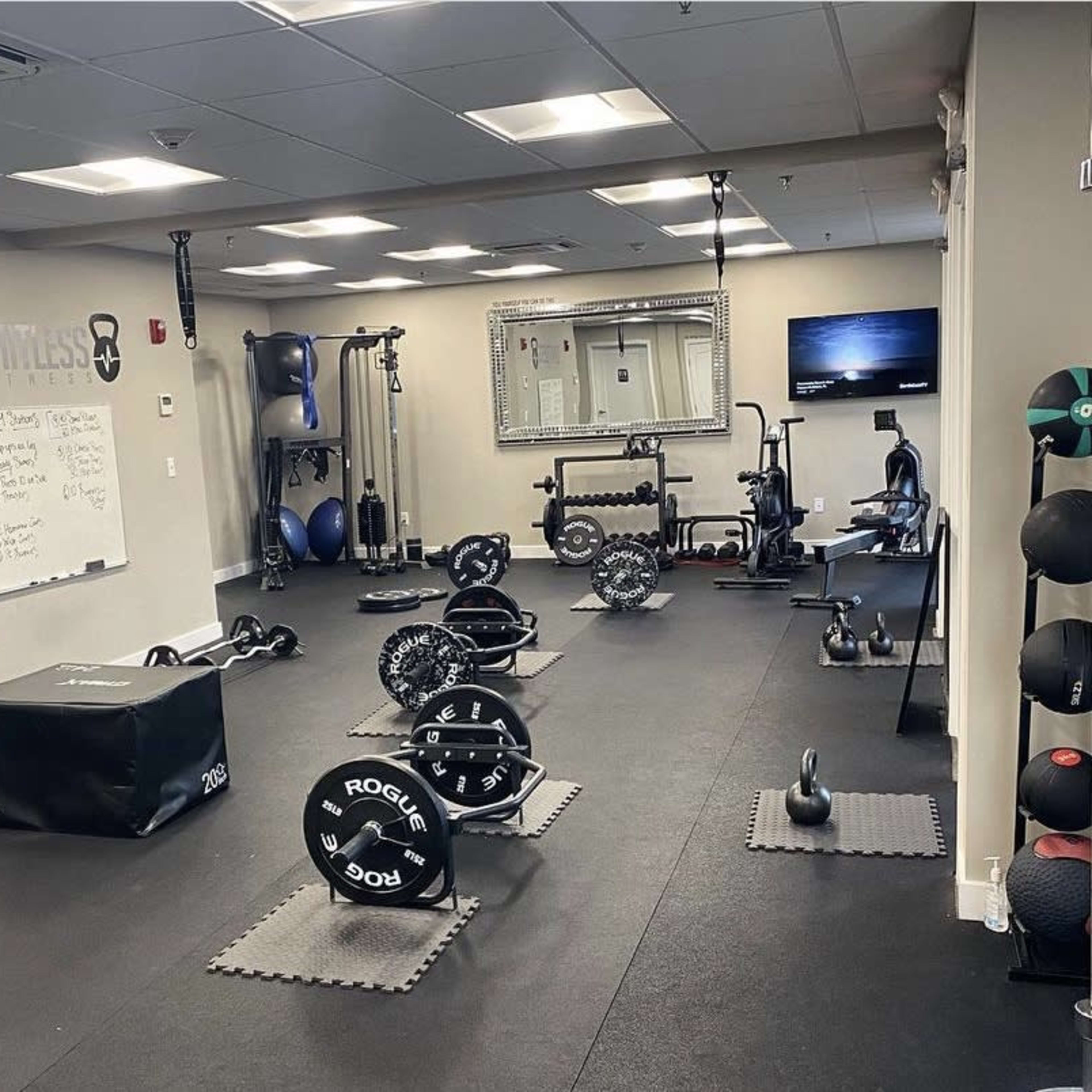 A well-equipped gym with various weightlifting and exercise equipment arranged across a carpeted floor.