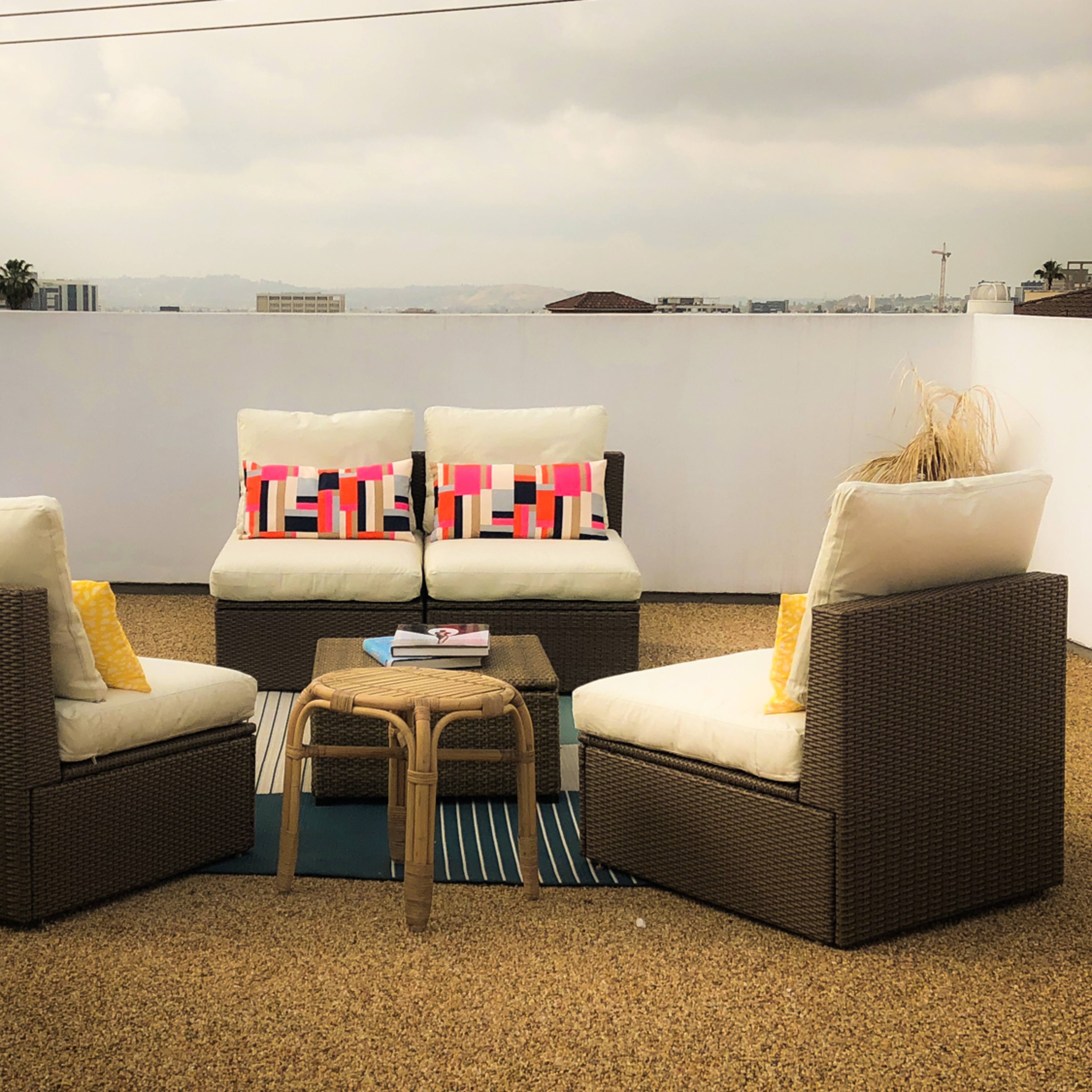 A modern outdoor seating area features four cushioned chairs and a central table on a patio with a view of the skyline.
