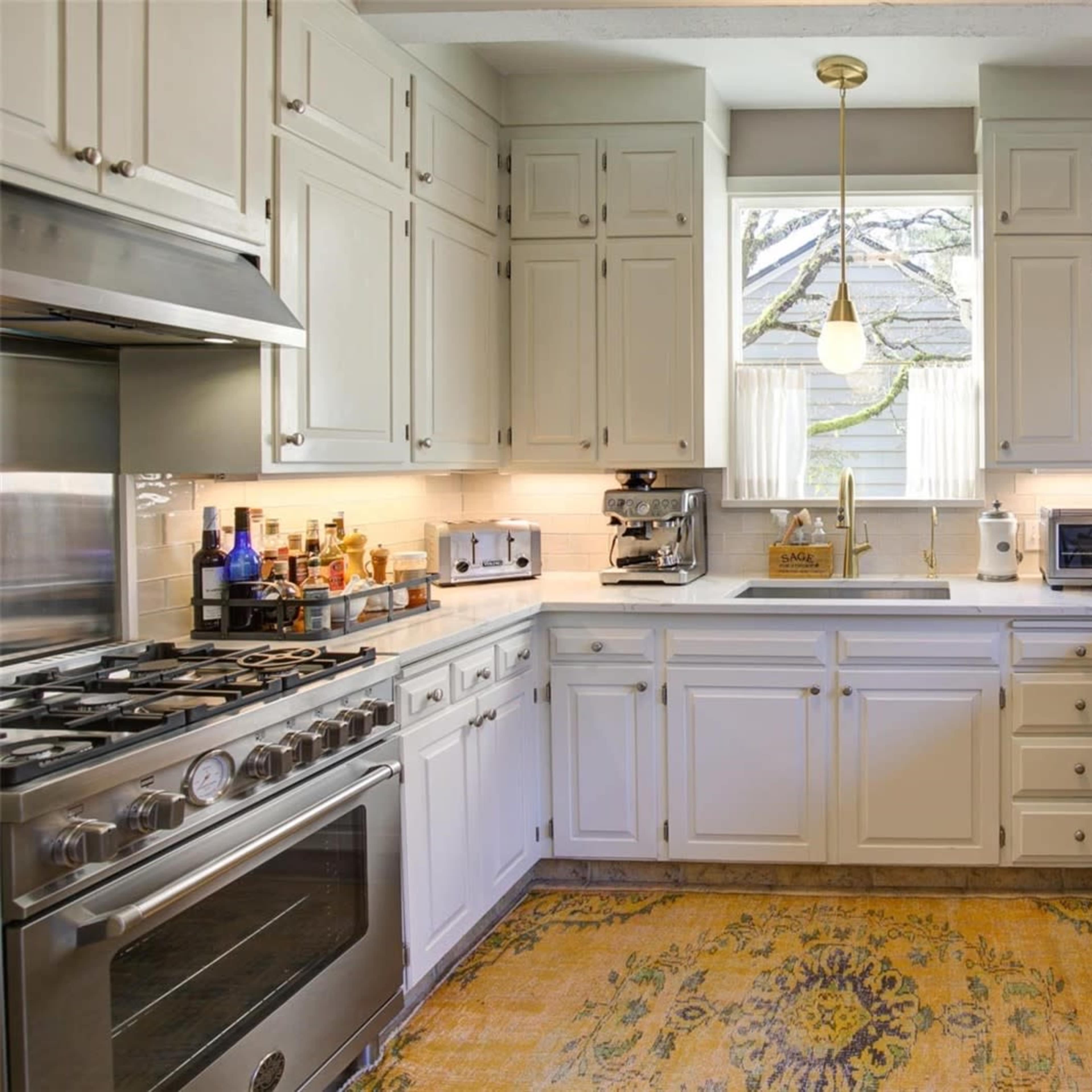 A modern kitchen with white cabinetry, stainless steel appliances, and a central island with a light-colored countertop.
