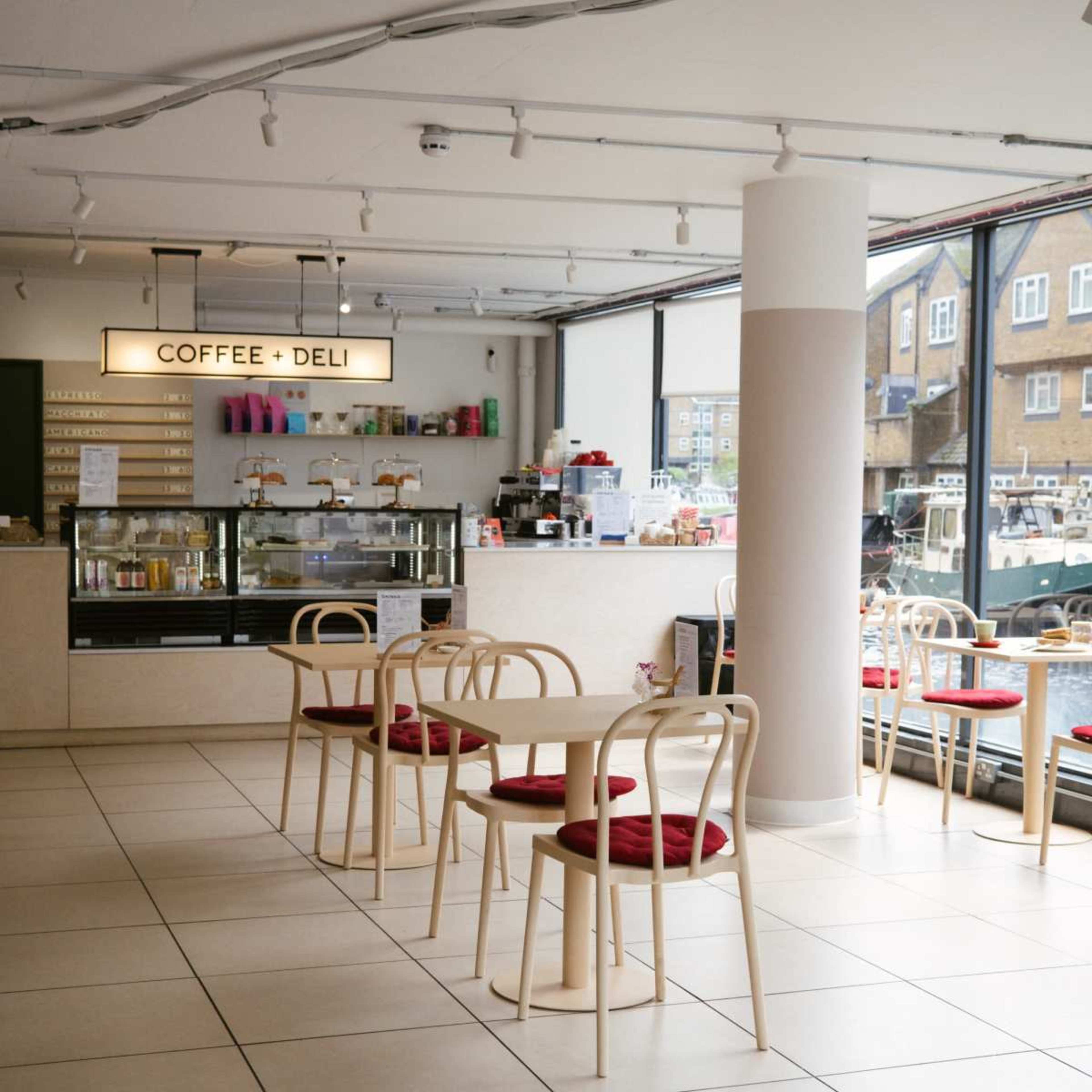 A modern coffee shop features a counter with various colorful items and minimalistic tables arranged in the seating area.