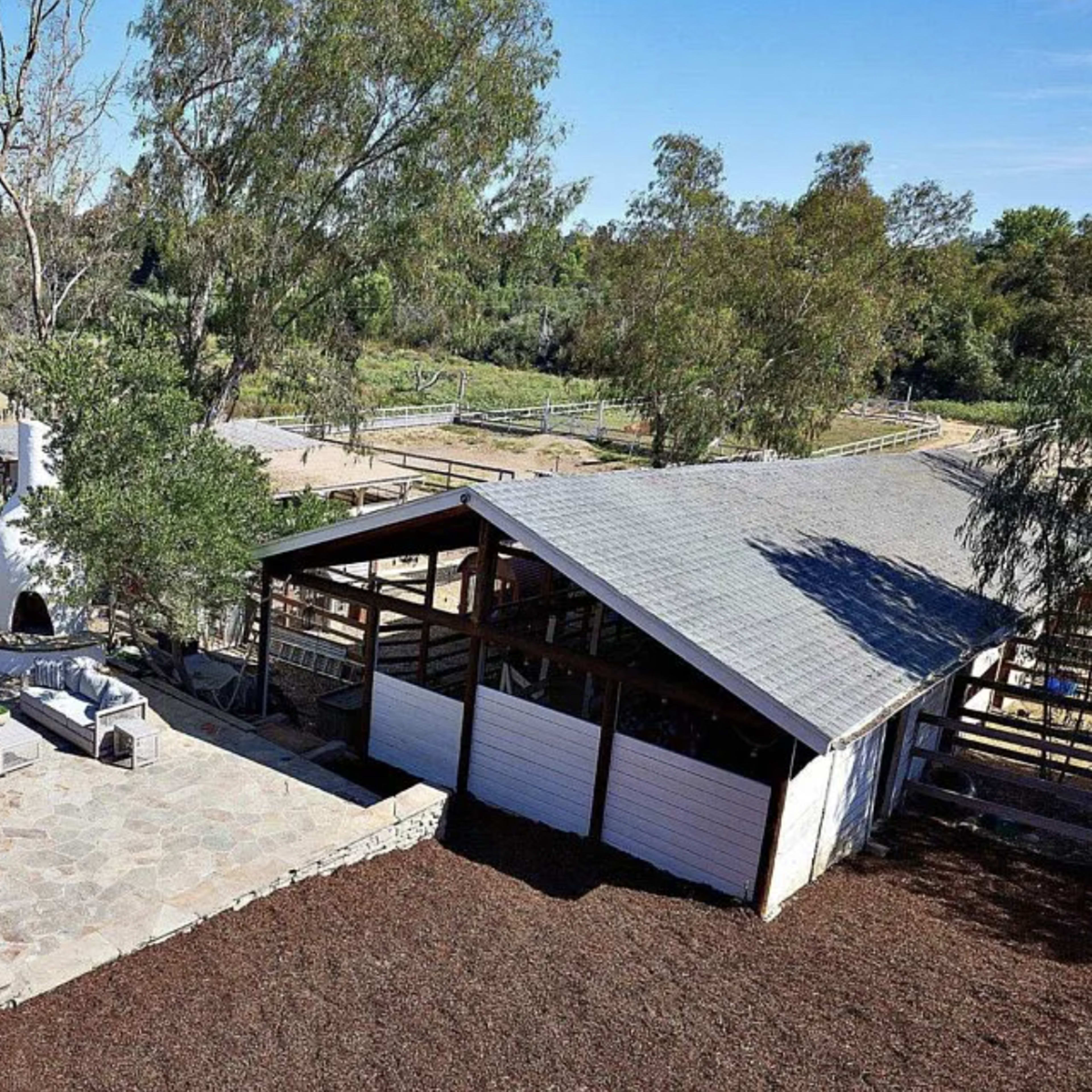 A spacious outdoor area with a stone patio, a seating arrangement, and a barn set in a green landscape.