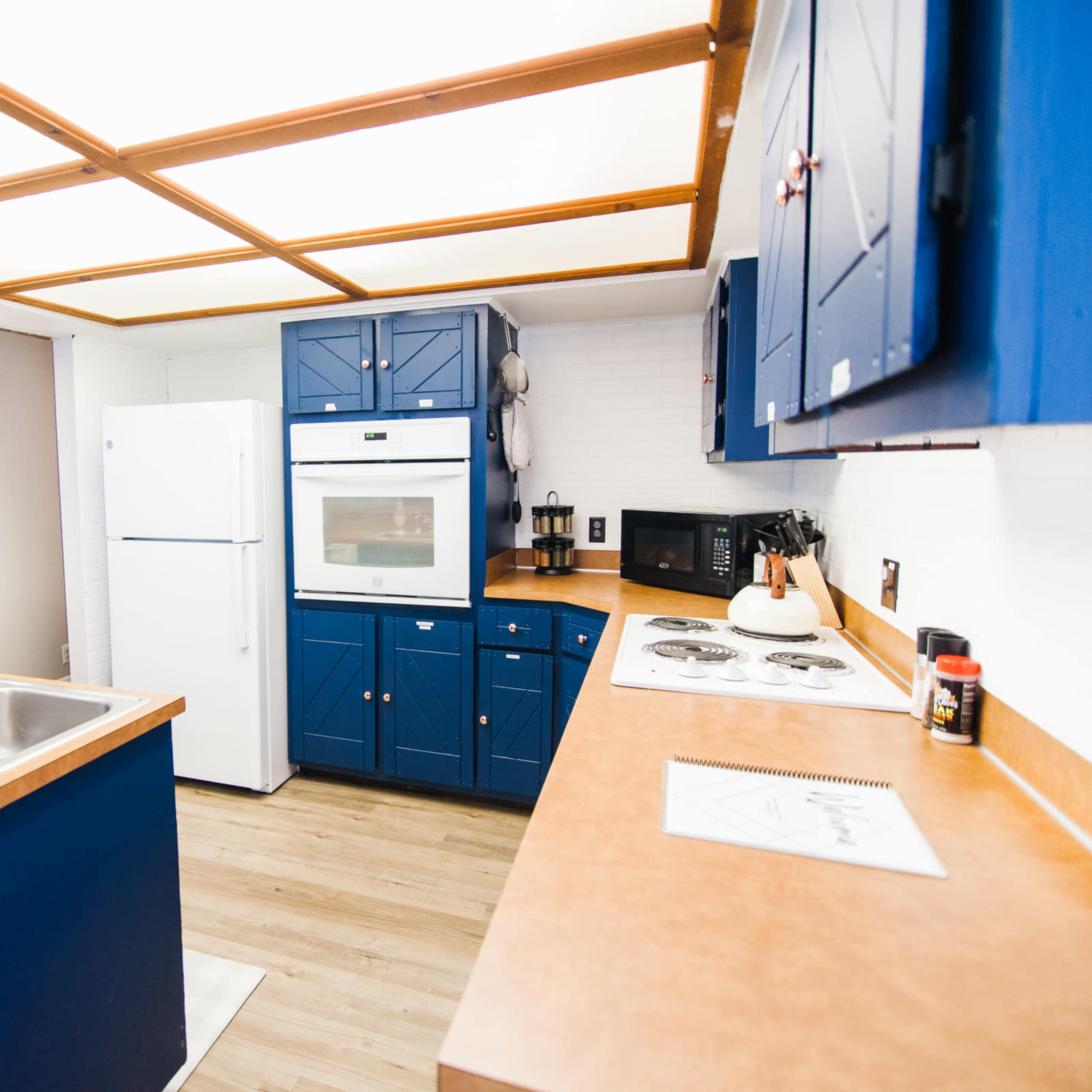 The kitchen features blue cabinetry, a white refrigerator, a built-in oven, and a countertop with a sink and stove.