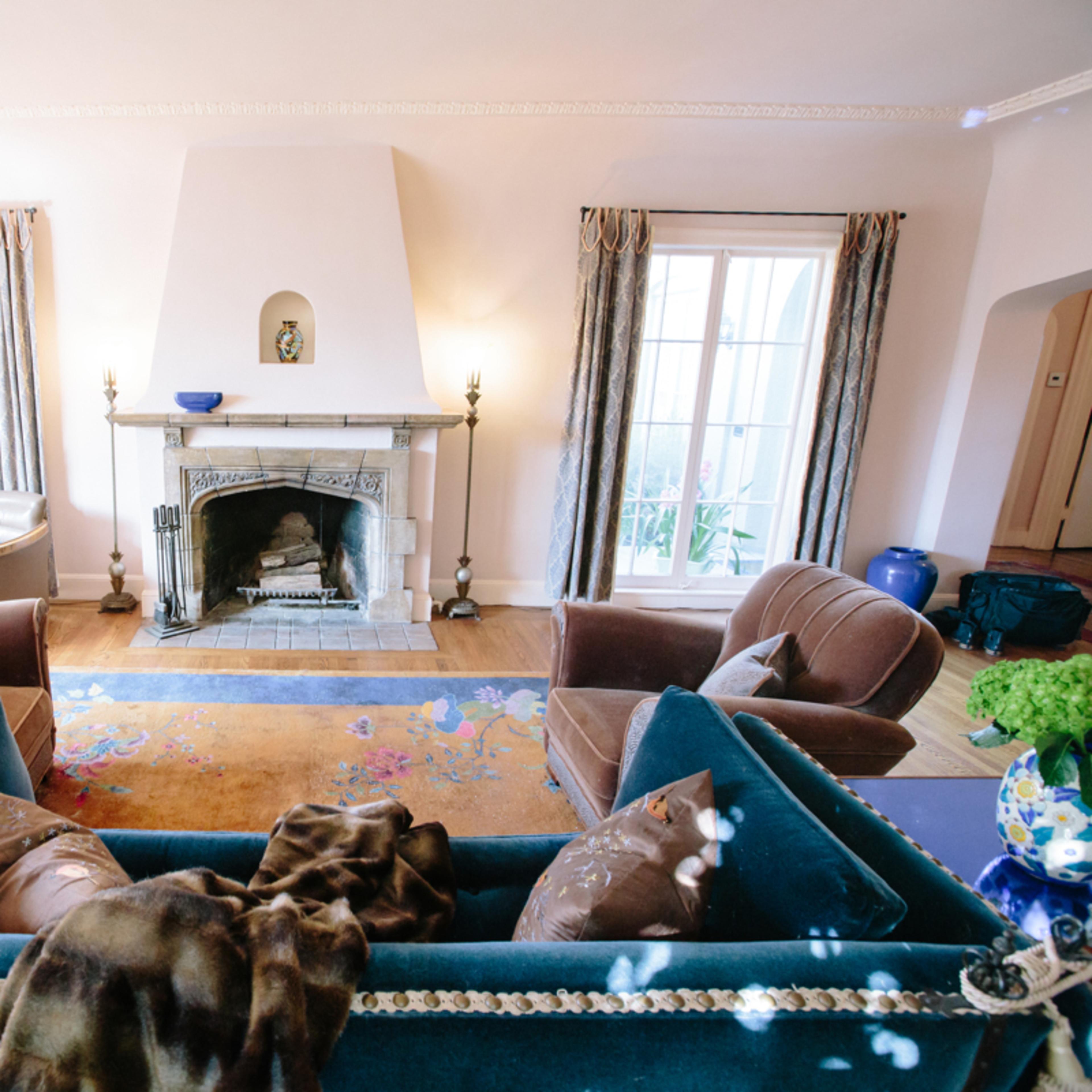 A cozy living room with a fireplace, two armchairs, and a blue sofa situated centrally in front of the fireplace.