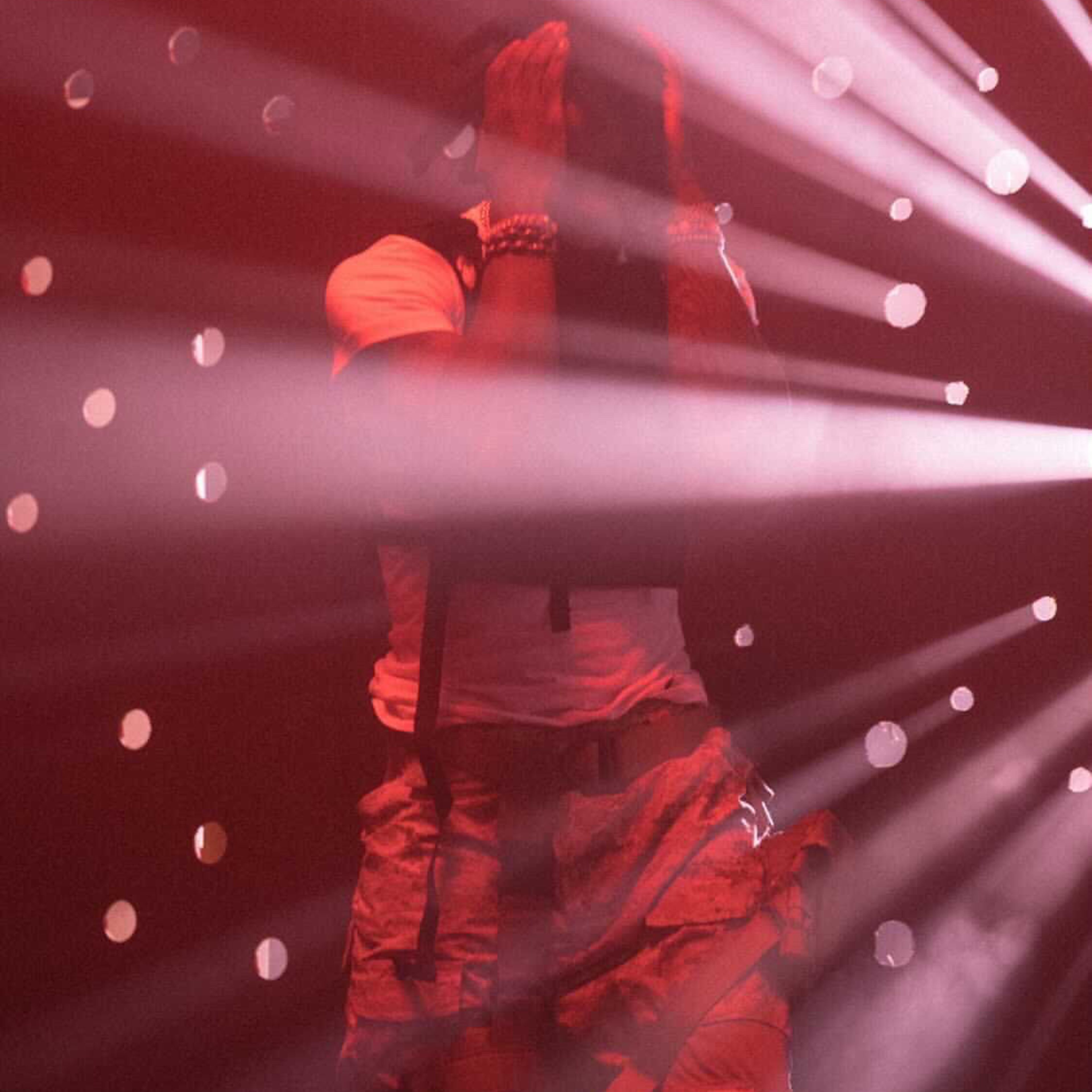 A silhouette of a person stands in front of lit beams and scattered points of light against a red background.