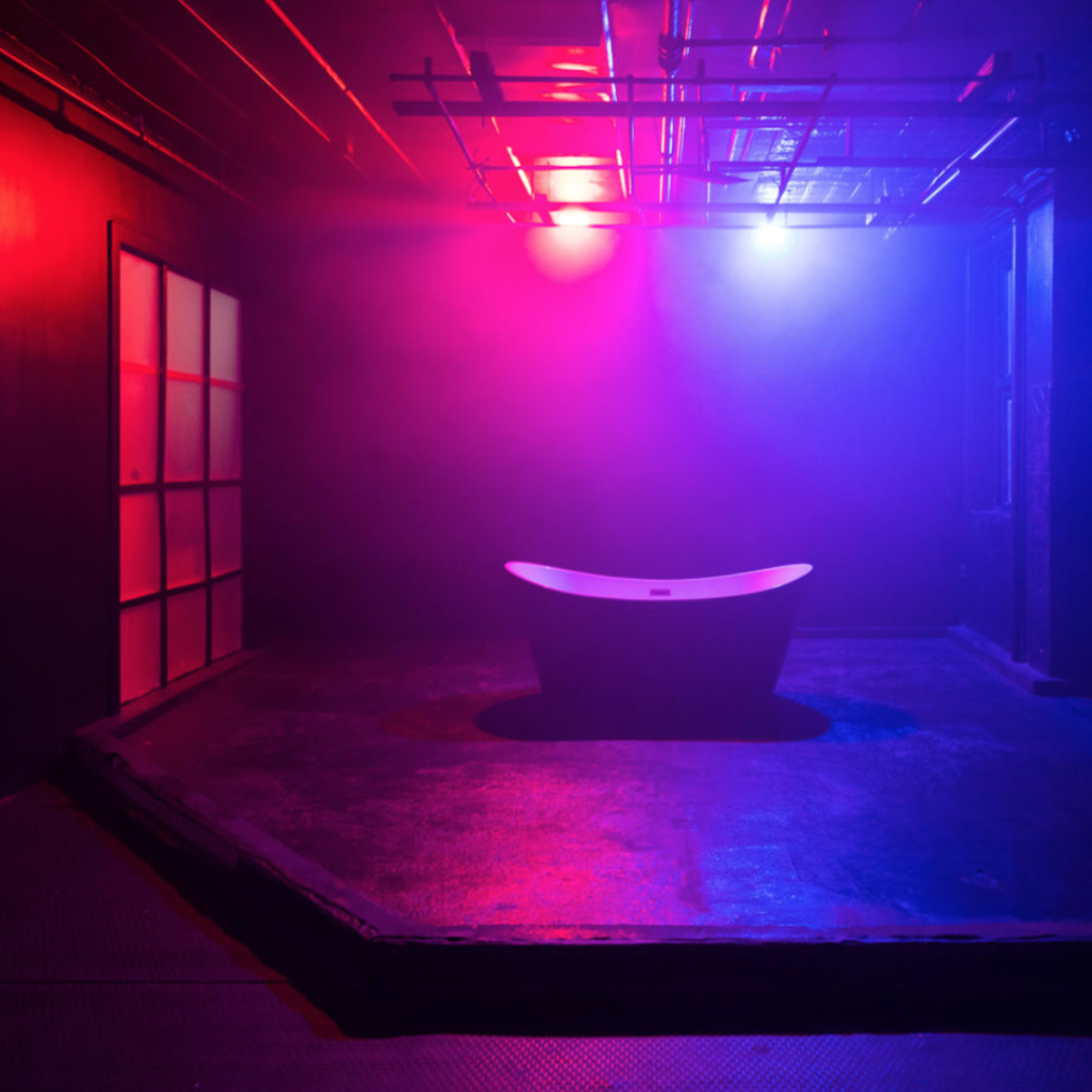 A motorcycle is parked in a dimly lit space with colorful neon lights and smoke effects.