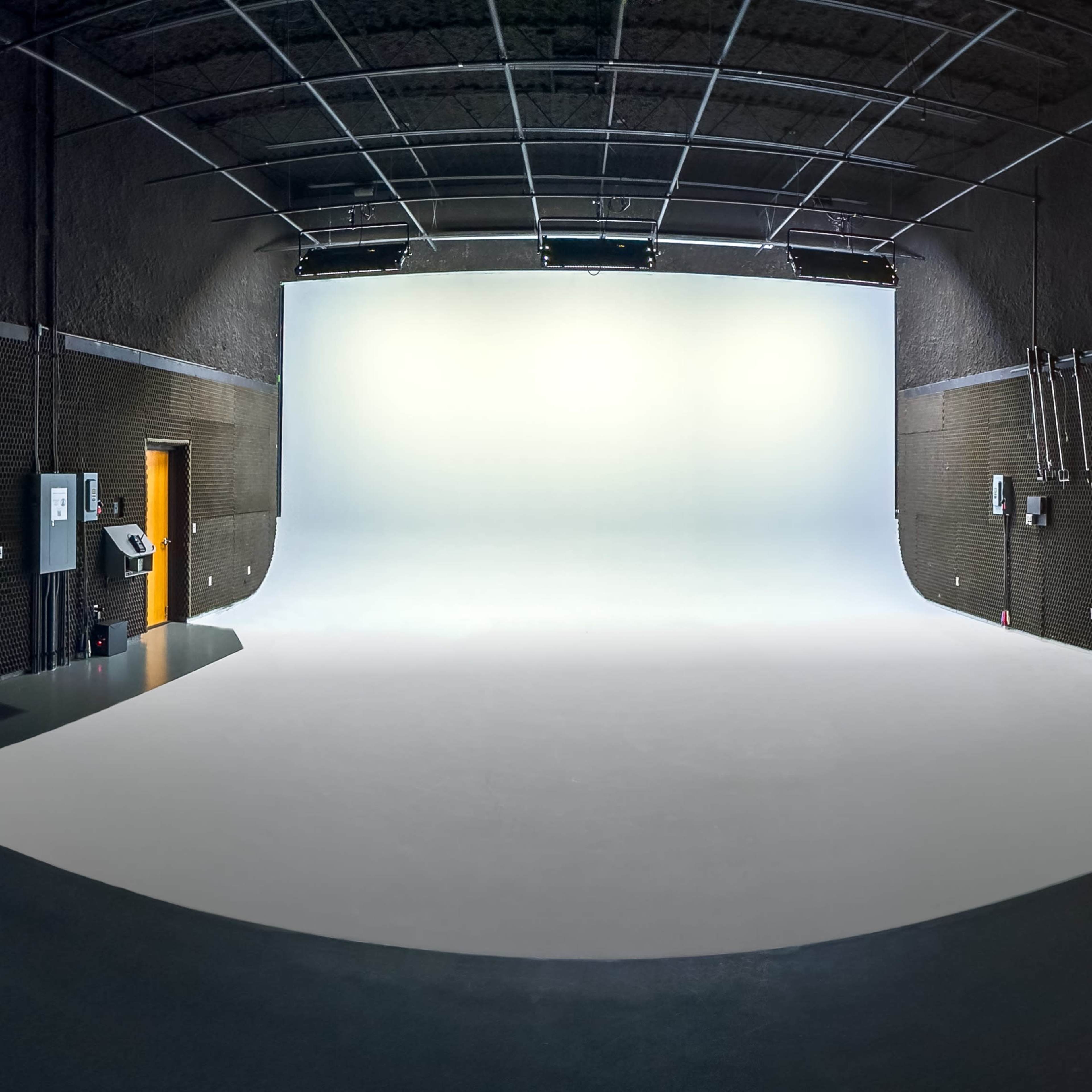 A spacious photography studio with a seamless white backdrop and gray walls.