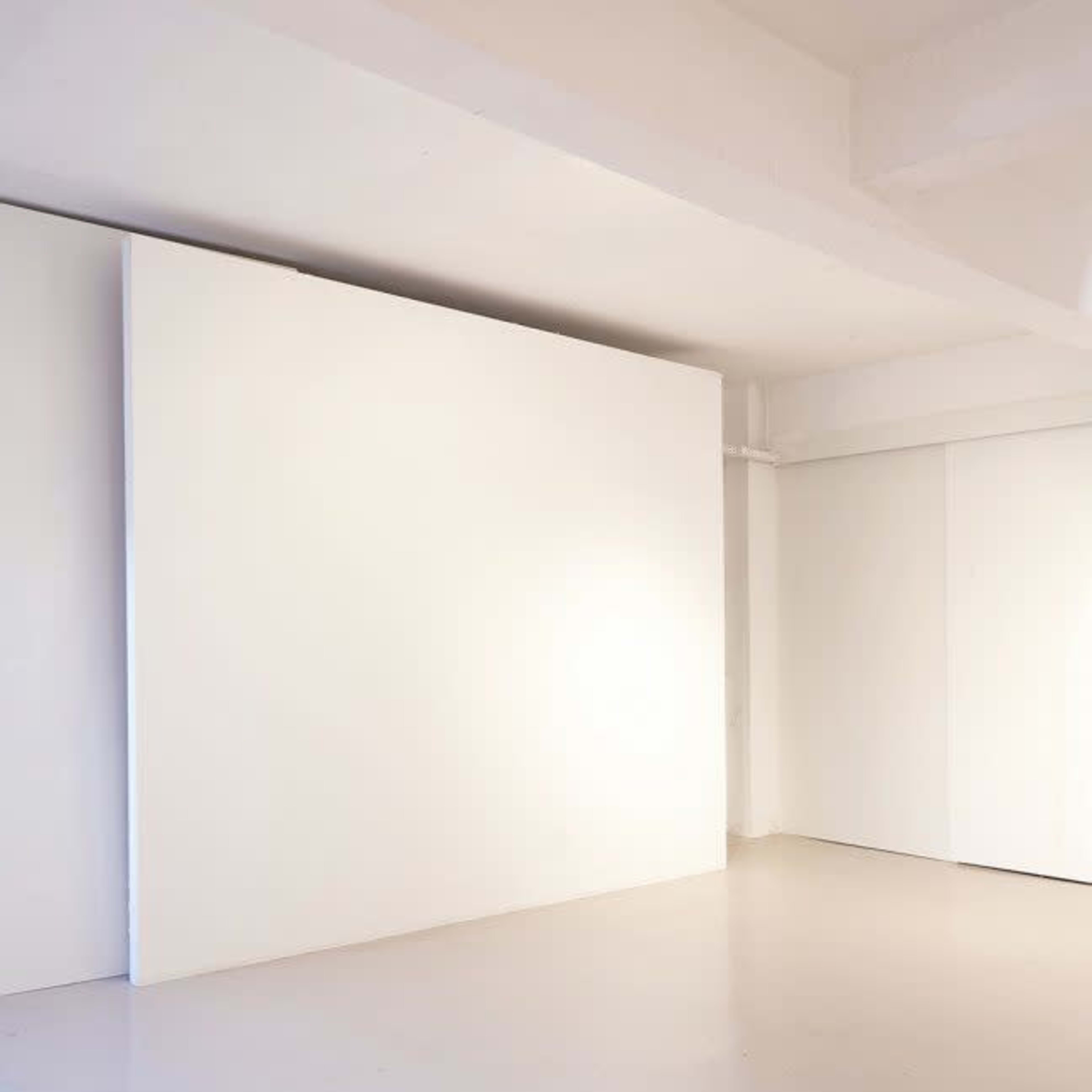A minimalist interior space with white walls and a light-colored floor.