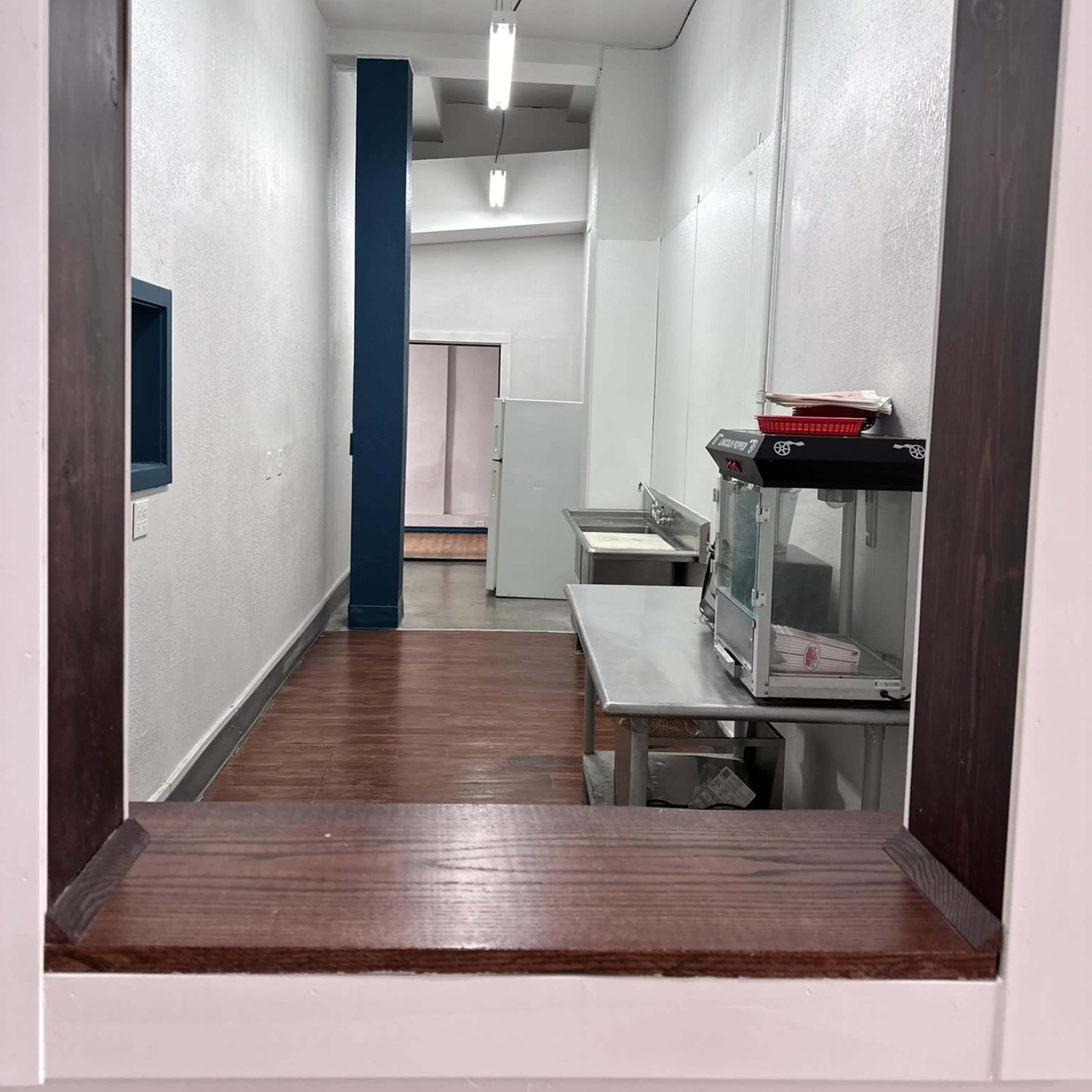 A narrow view of a corridor with white walls and several stainless steel tables.