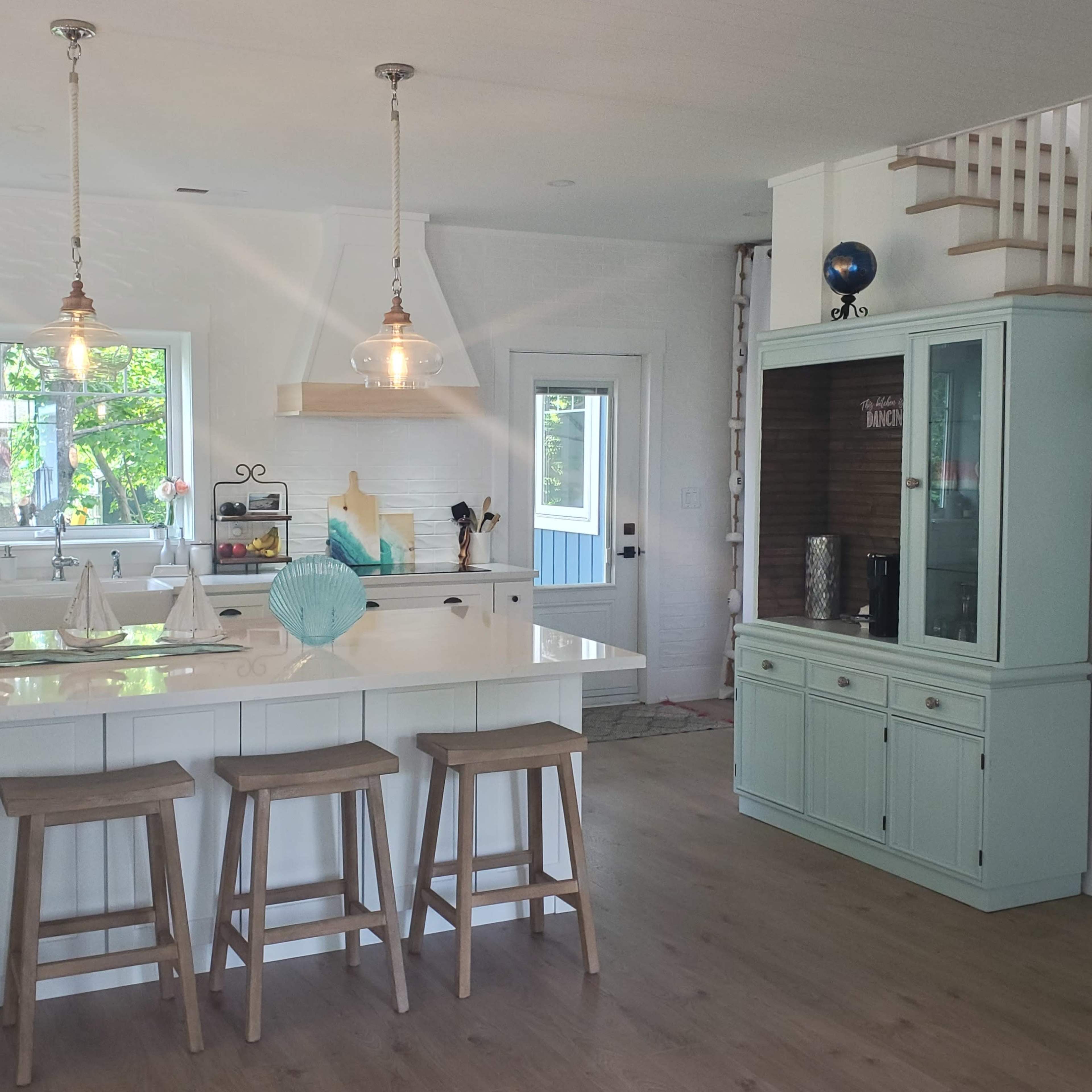 A modern kitchen equipped with a large island, barstools, and a mix of wood and white cabinetry.