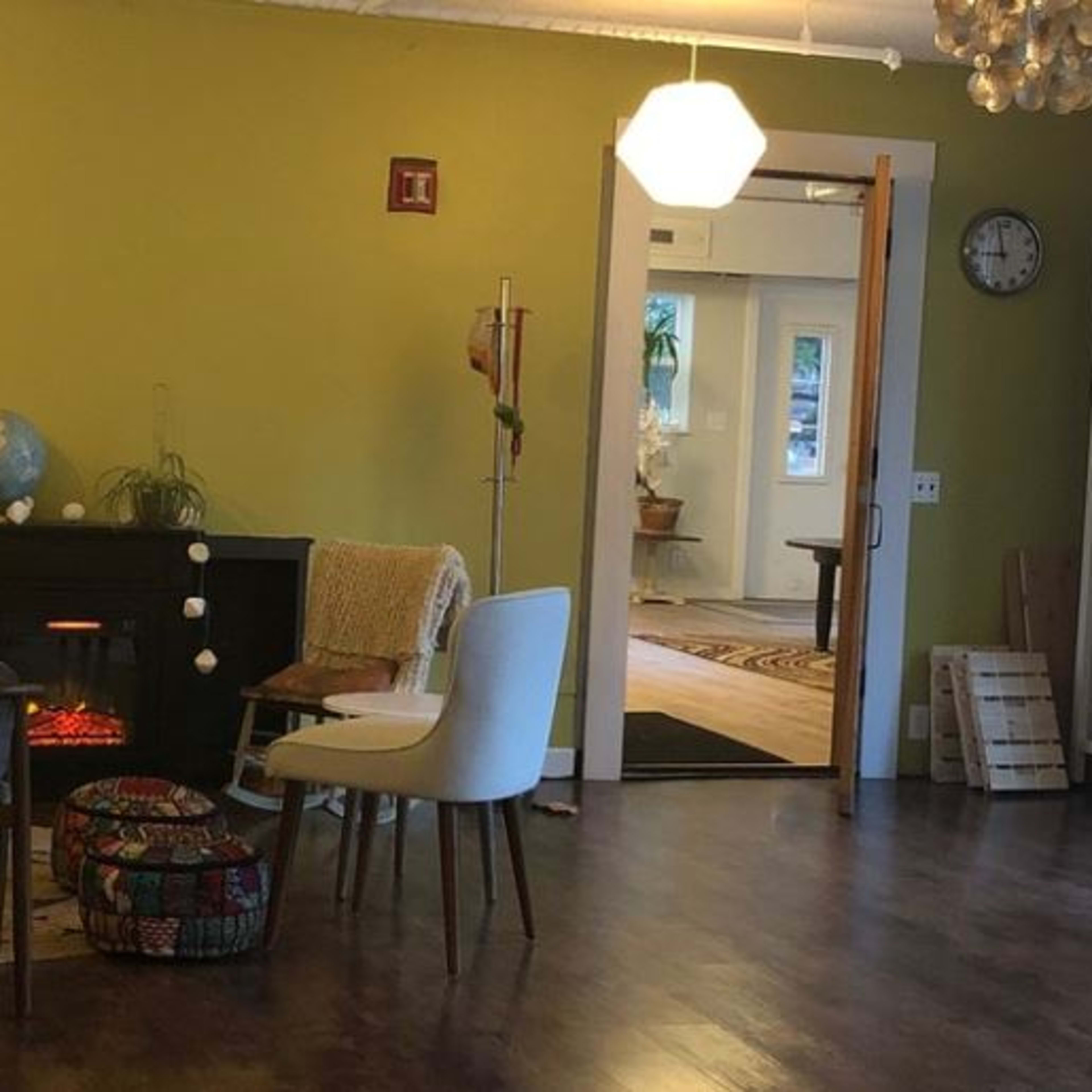 A spacious living room with a green accent wall, a piano, a globe on a stand, and various plants around the area.